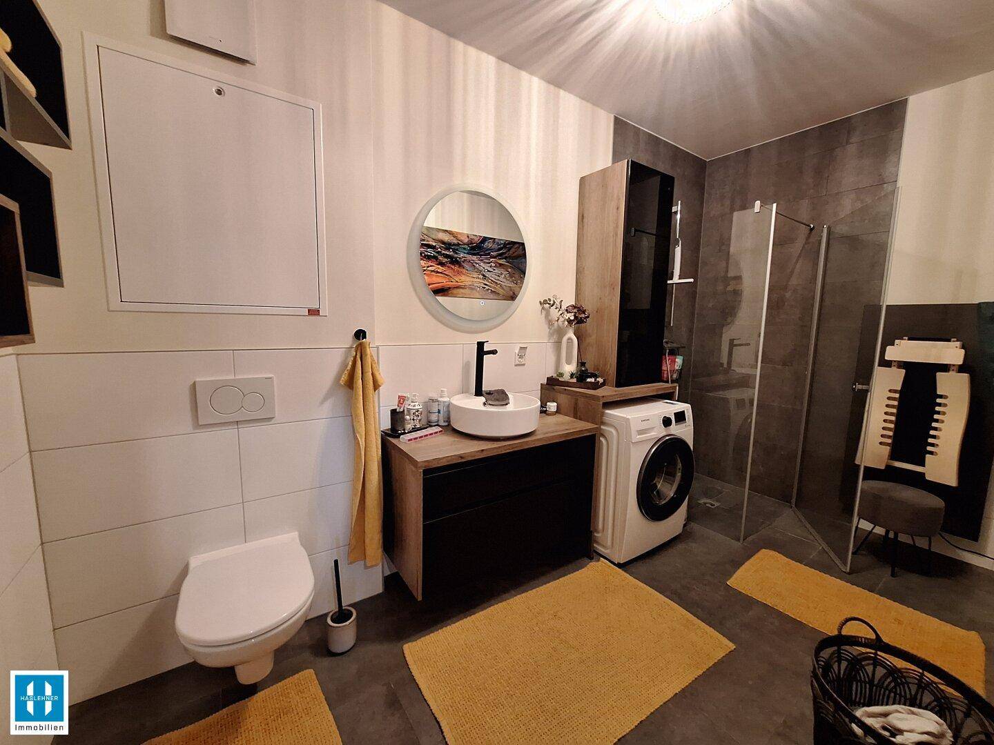 Modernes Badezimmer mit Dusche, Waschmaschine und stilvollem Waschbecken.