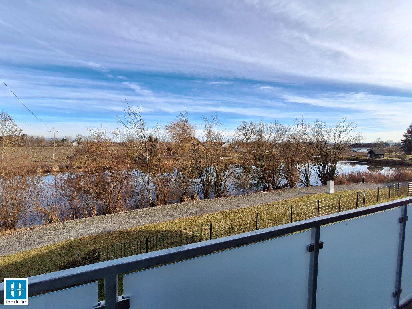Panoramablick vom Balkon auf einen See und die grüne, ländliche Umgebung.