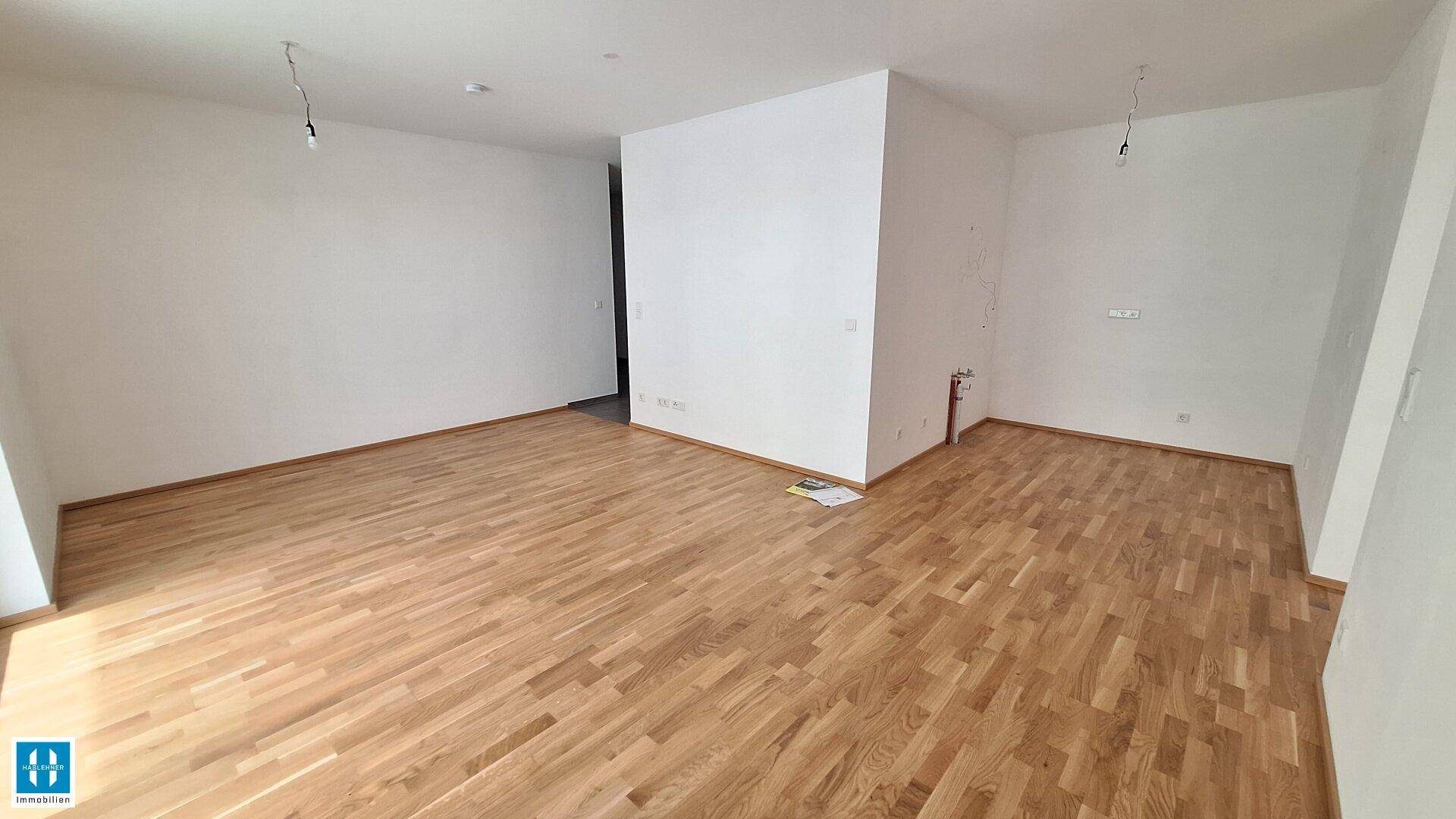 Leerer Raum mit Holzboden und weißen Wänden, bereit für individuelle Gestaltung.