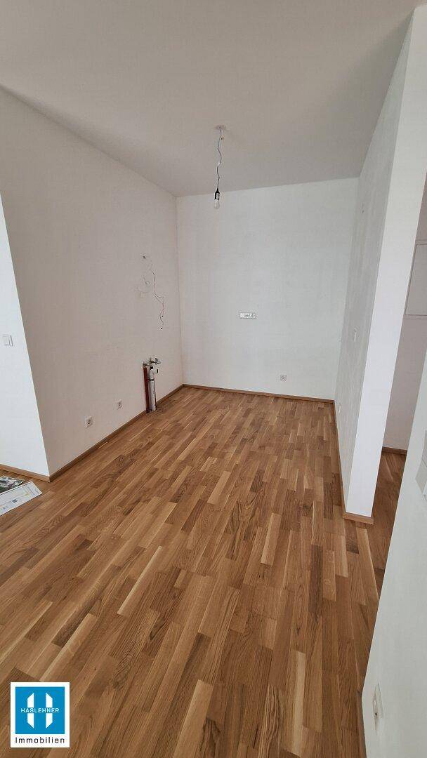 Unmöblierter Raum mit Holzboden und weißen Wänden, ideal für individuelle Nutzung.