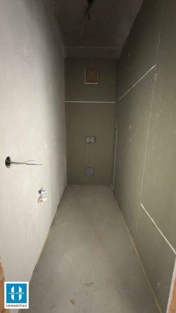 Kleiner, unfertiger Raum mit Trockenbauwänden und Betonboden, bereit für die Endmontage.