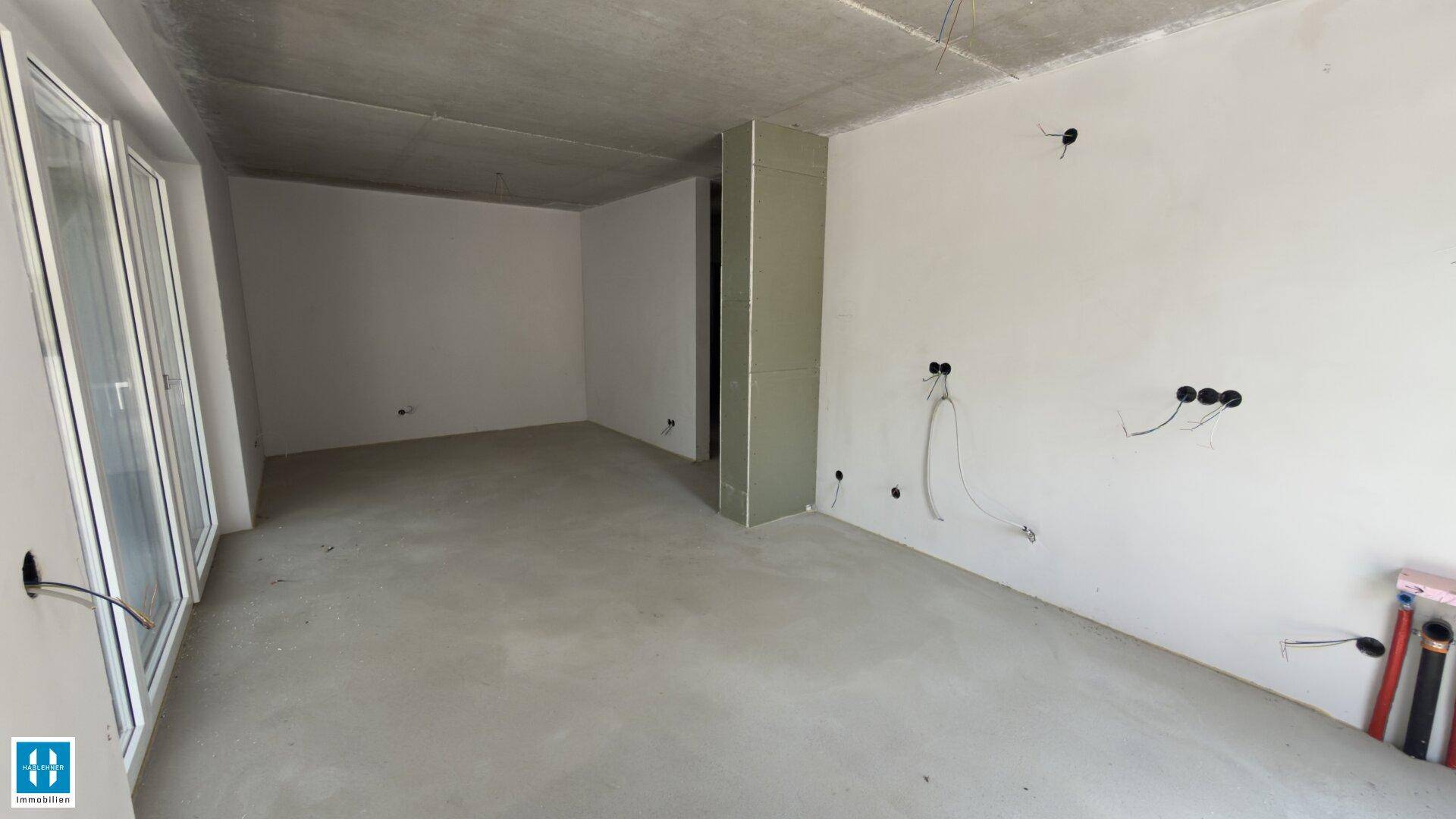 Heller, unfertiger Raum mit Betonboden und großen Fenstern, ideal für individuelle Gestaltung.
