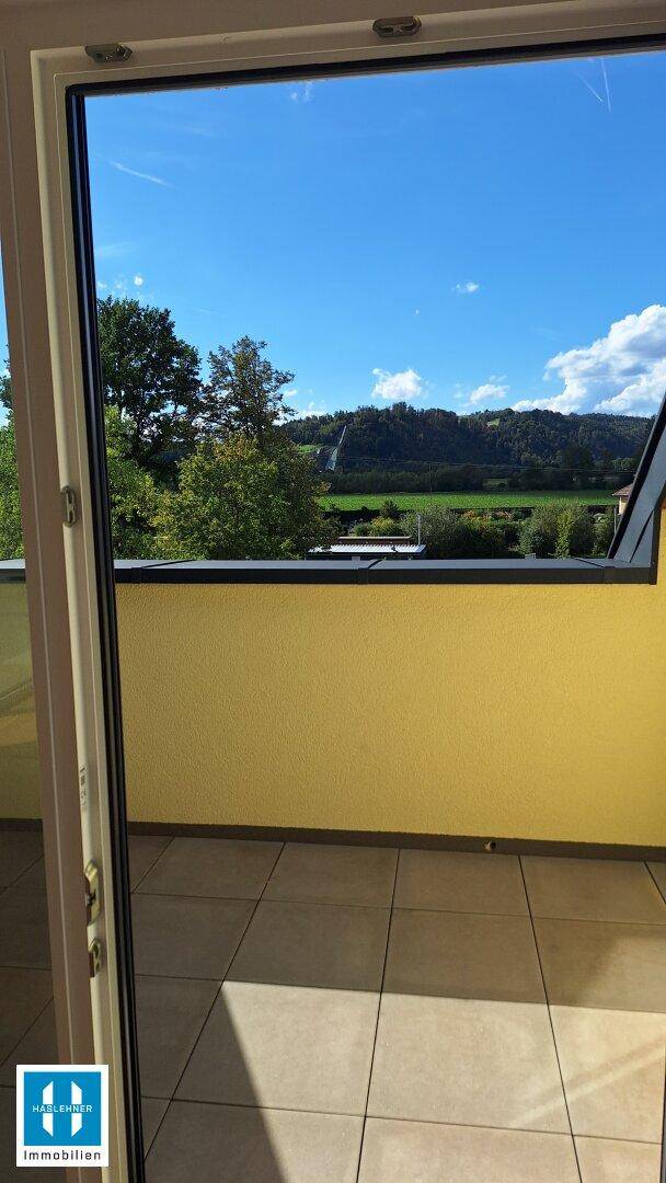 Panoramablick von der Terrasse auf die umliegende grüne Landschaft und den blauen Himmel.