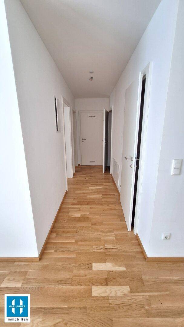 Langer Flur mit hellem Parkettboden und mehreren Türen, der die Zimmer verbindet.
