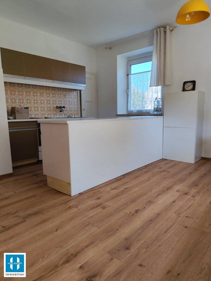 Küche mit Kücheninsel, Laminatboden und Fenster, bereit zur individuellen Gestaltung und Nutzung.