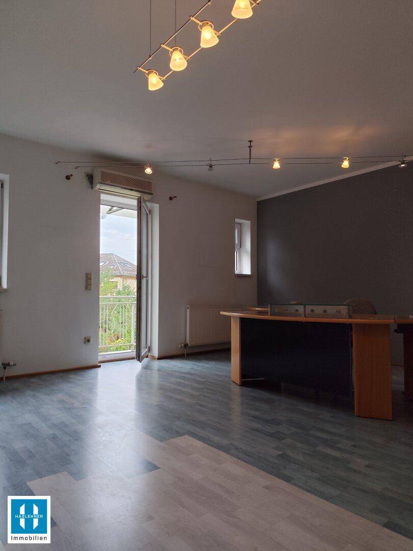 Heller Raum mit Laminatboden und Schreibtisch, mit Zugang zu einem kleinen Balkon.