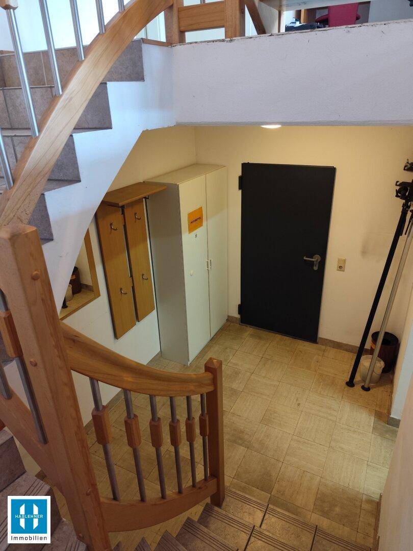 Eingangsbereich mit gefliester Treppe, dunkler Tür und praktischem Wandschrank.