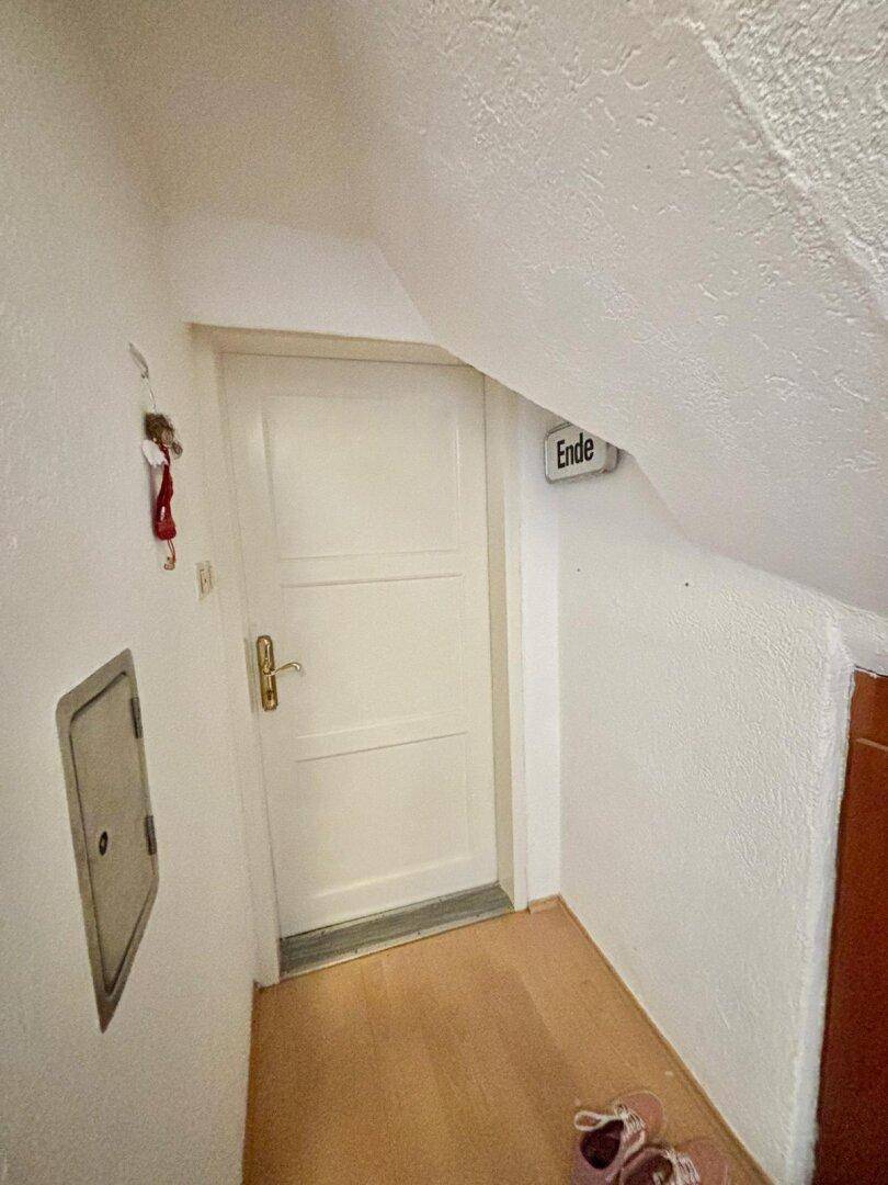 Kleiner Flur mit Dachschräge und einer Tür, die zu einem weiteren Raum führt.