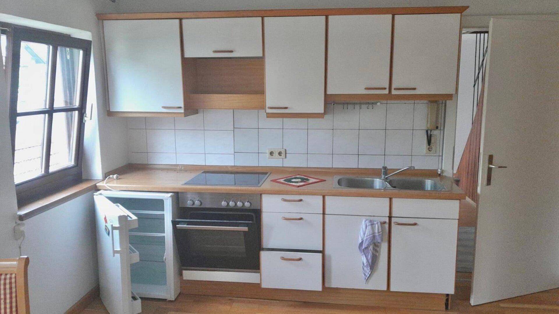Funktionale Küche mit weißen Schränken, Holztheke und integrierten Geräten.