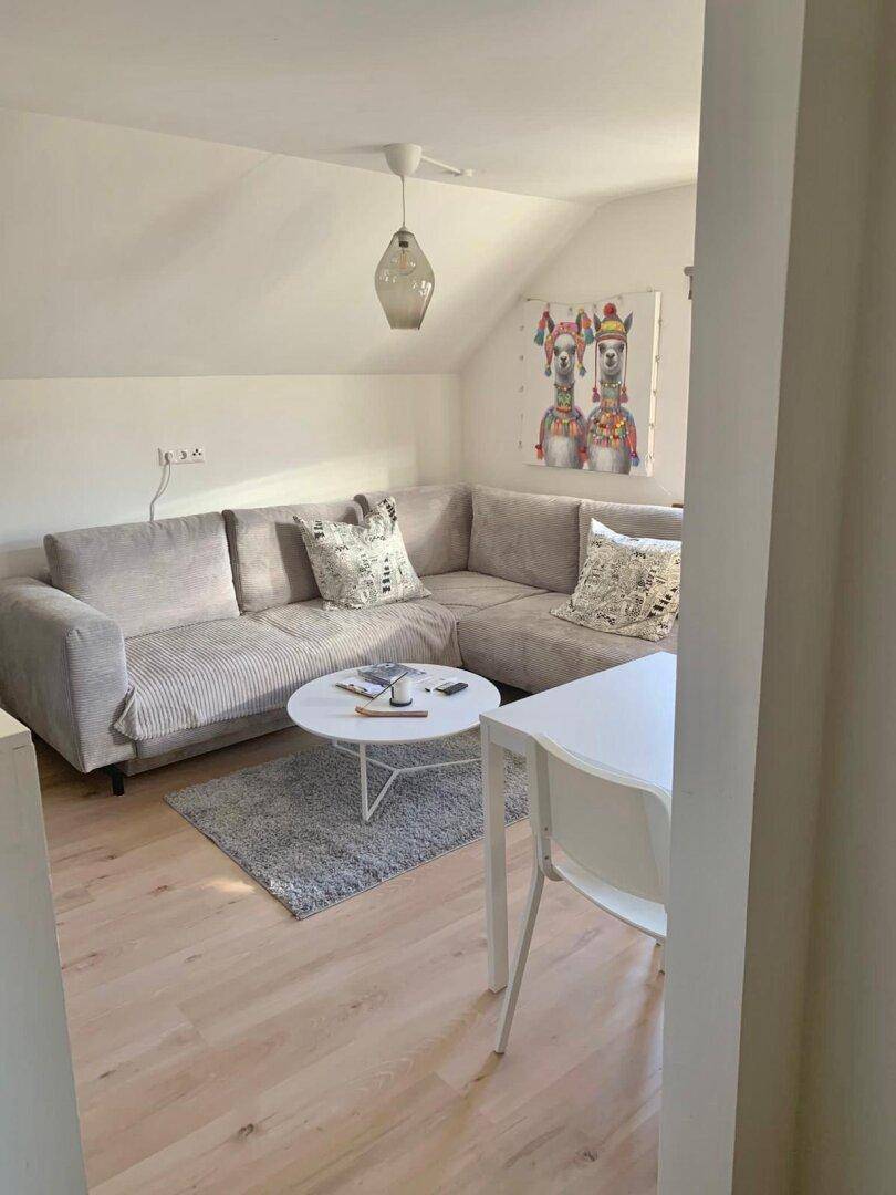 Helles Wohnzimmer im Dachgeschoss mit Ecksofa, Couchtisch und moderner Dekoration.