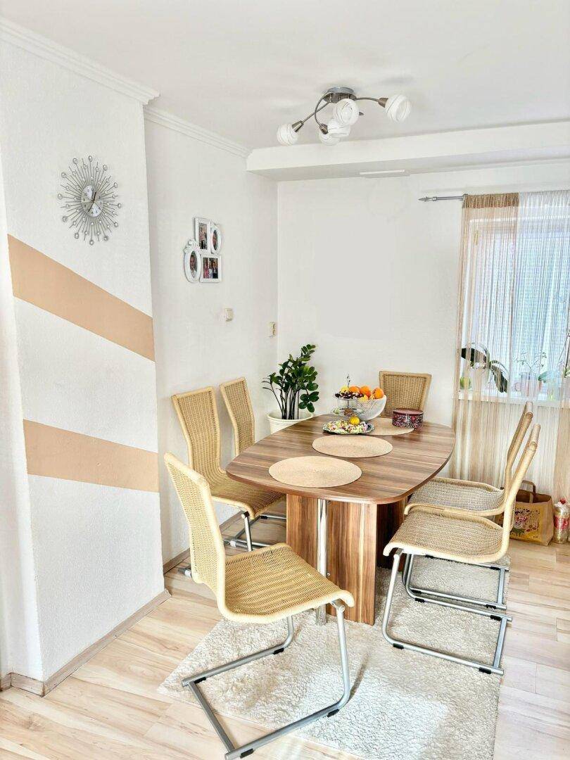 Heller Essbereich mit Holztisch, modernen Stühlen und dekorativer Wandgestaltung.
