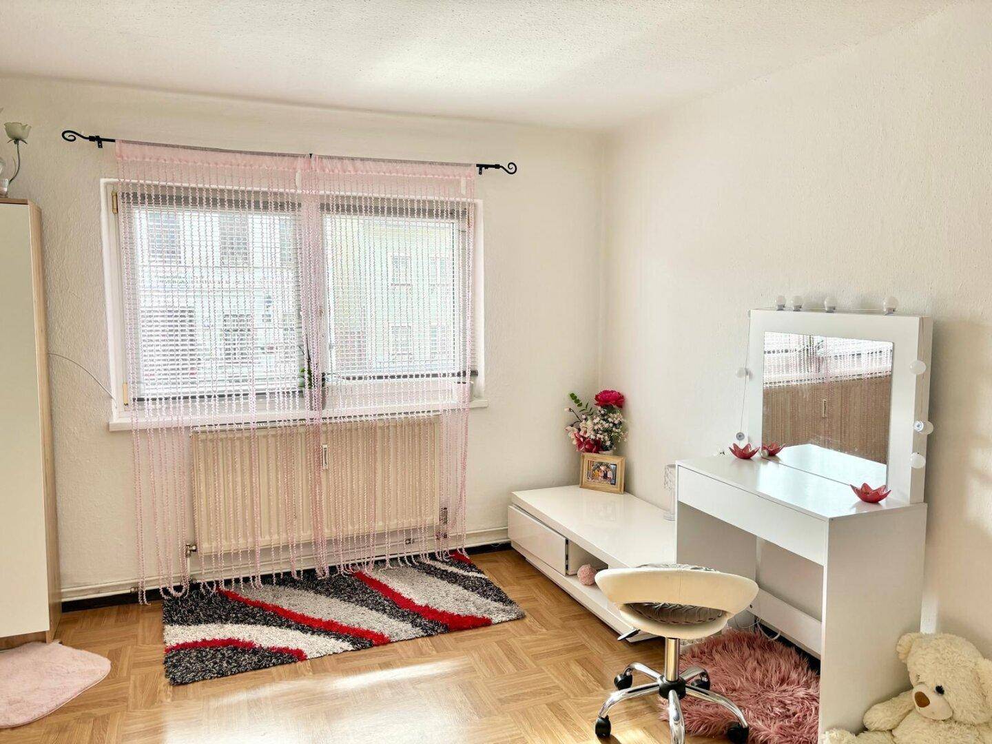 Schlafzimmer mit Schminktisch, großem Fenster und hellem Ambiente.