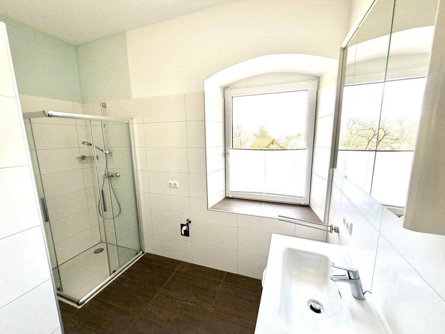 Modernes Badezimmer mit Duschkabine, Waschbecken und Fenster für natürliches Licht.