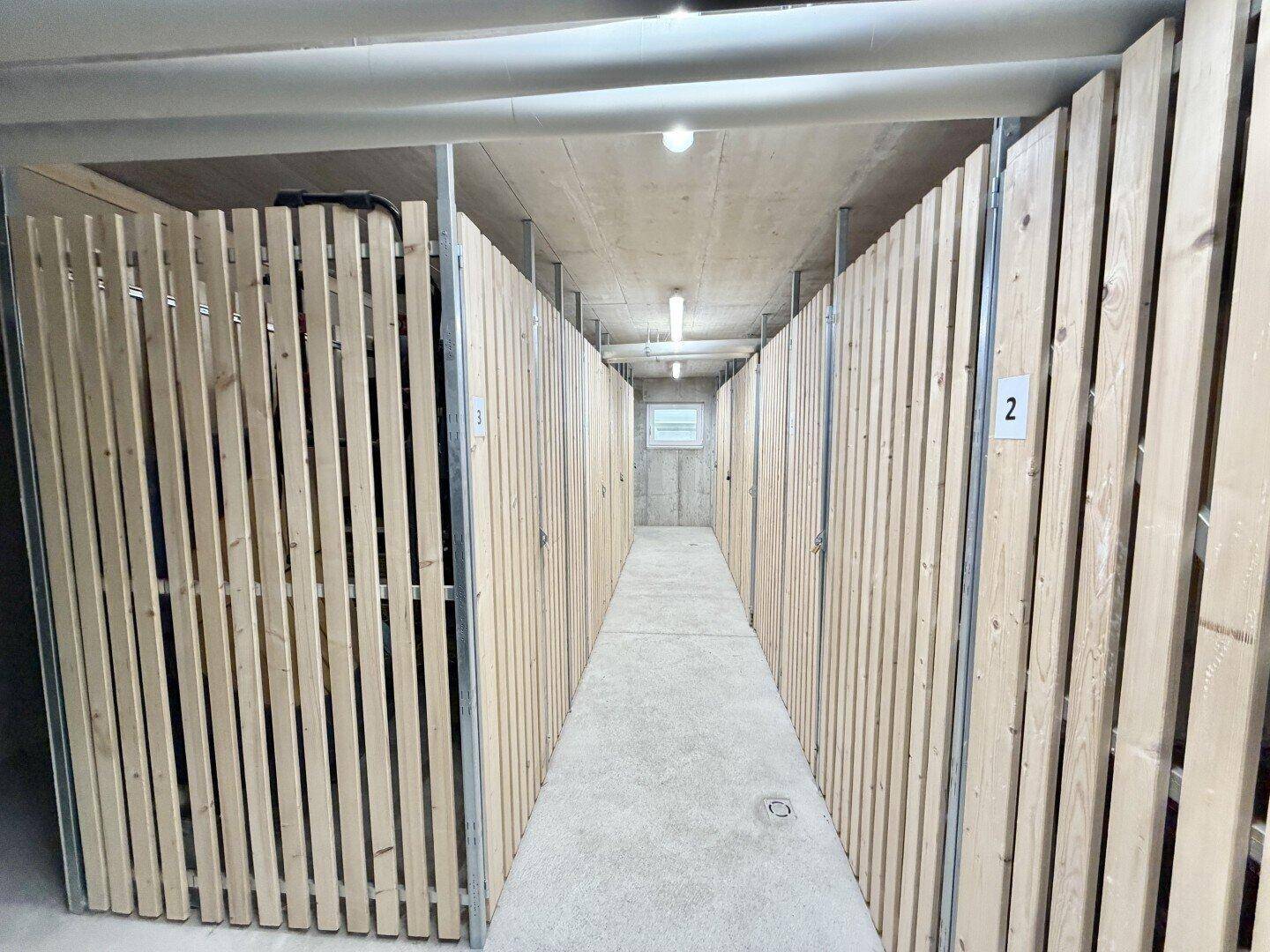 Geräumiger Abstellraum im Keller mit einzelnen Holzverschlägen für jede Wohneinheit.