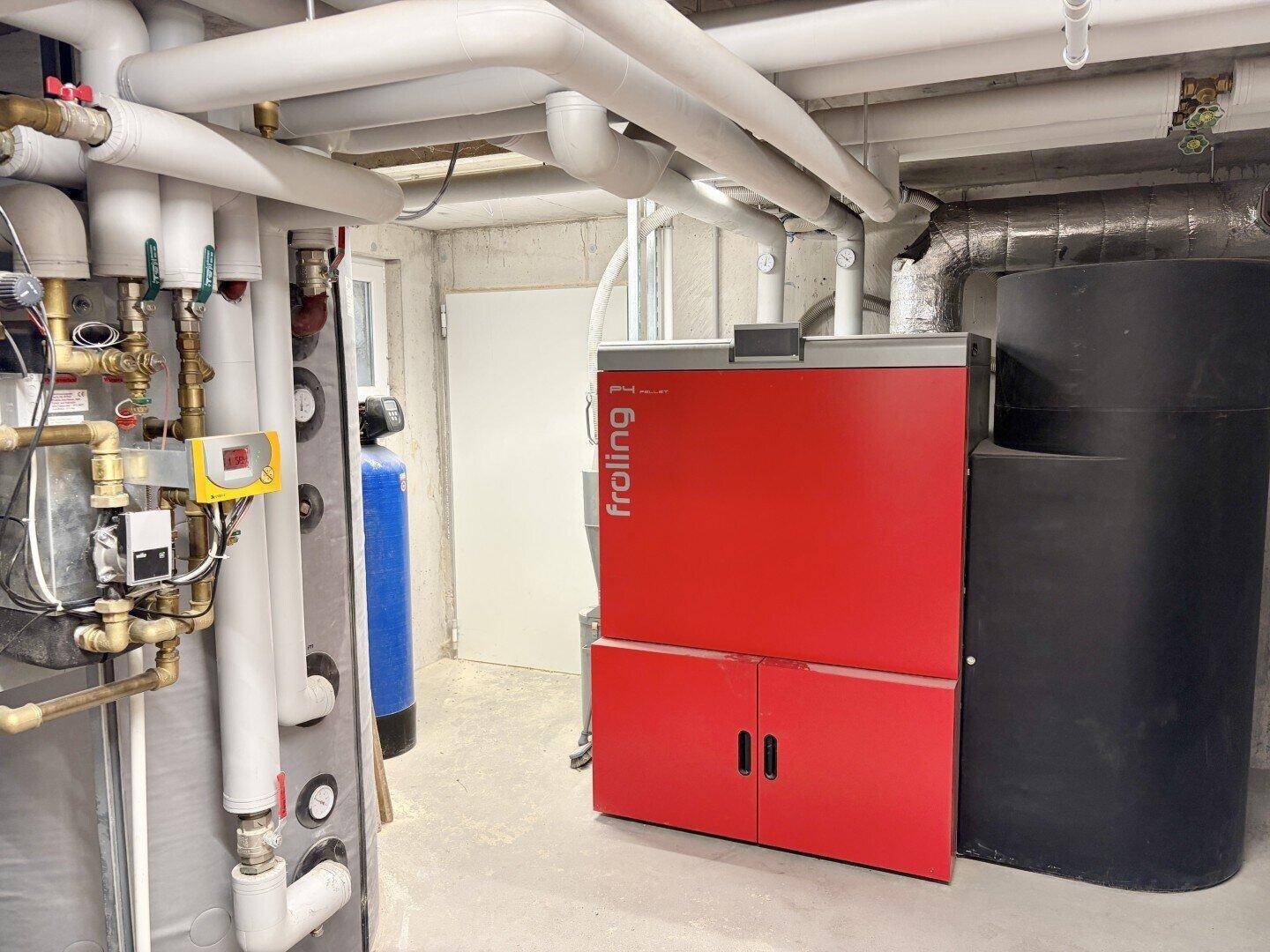 Heizungsraum im Keller mit moderner Pelletheizung und Warmwasserspeicher.