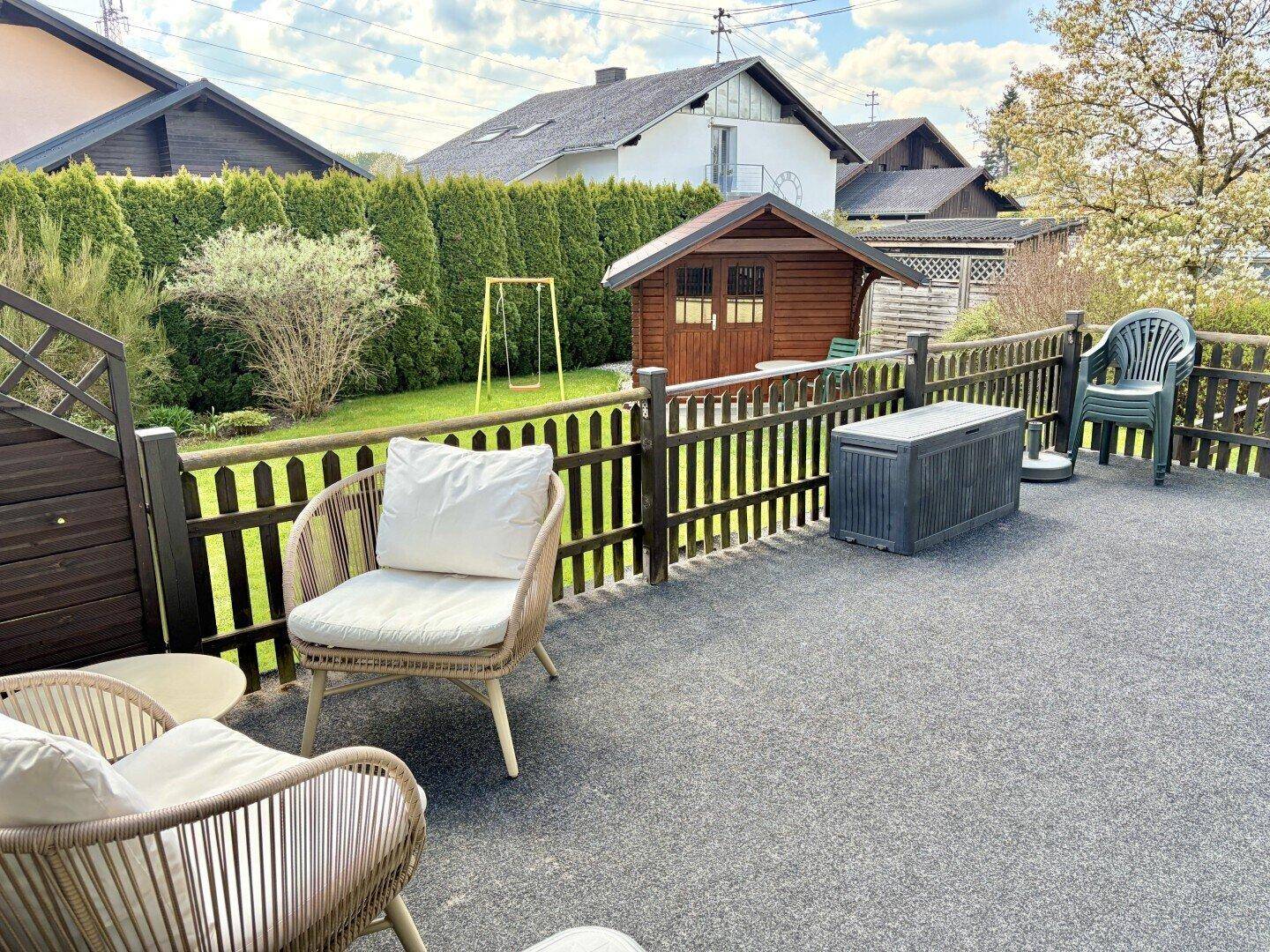 Große Terrasse mit Sitzgelegenheiten und Blick auf den Garten und die Umgebung.