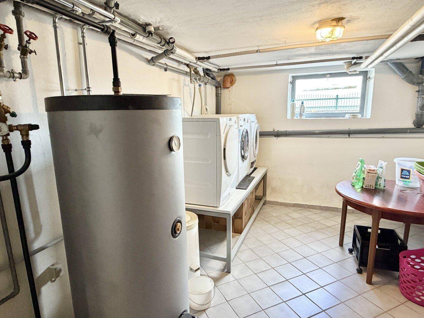 Praktischer Hauswirtschaftsraum im Keller mit Waschmaschinen und Warmwasserspeicher.