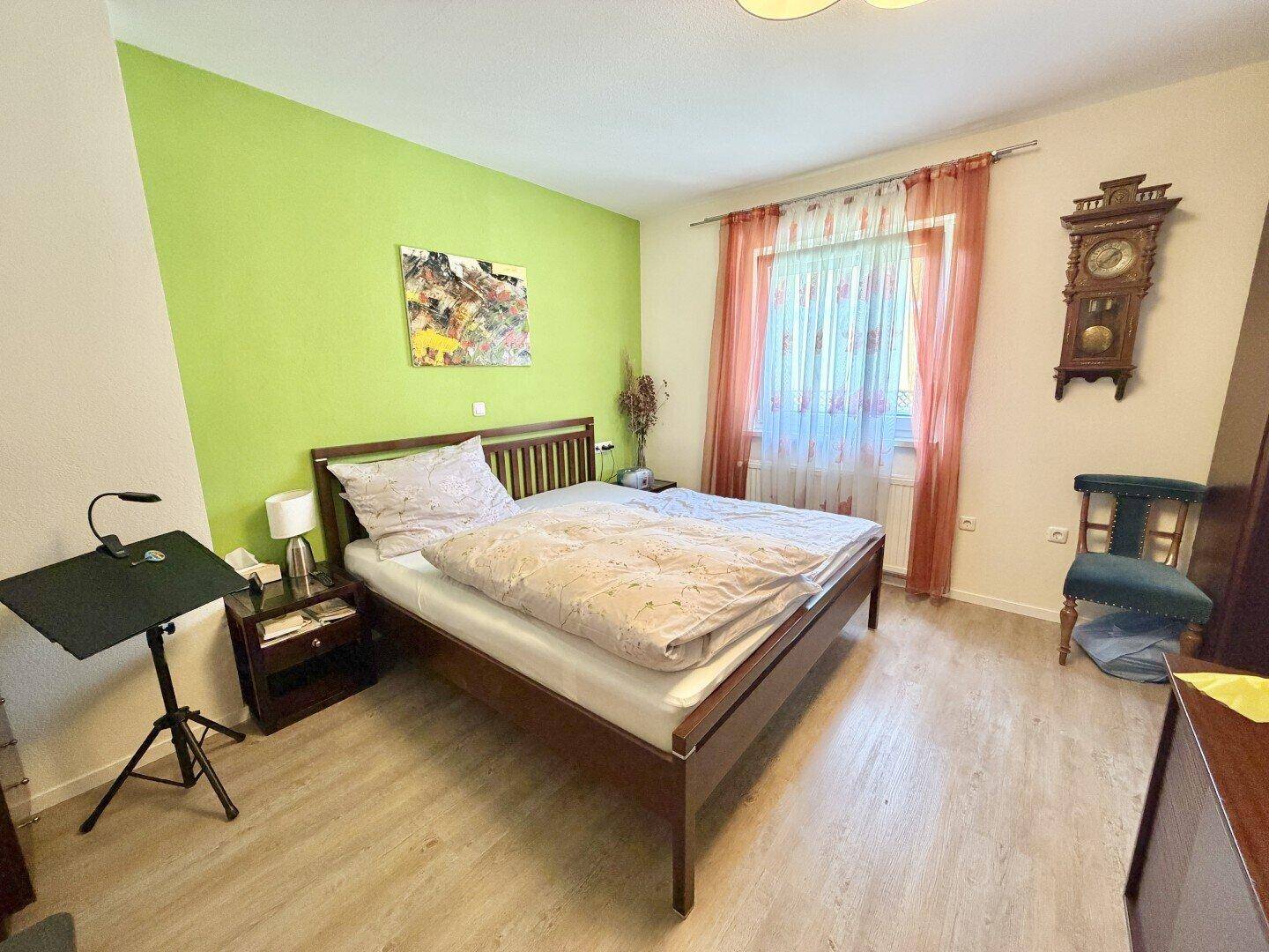 Gemütliches Schlafzimmer mit Holzbett, grün gestrichener Wand und Laminatboden.