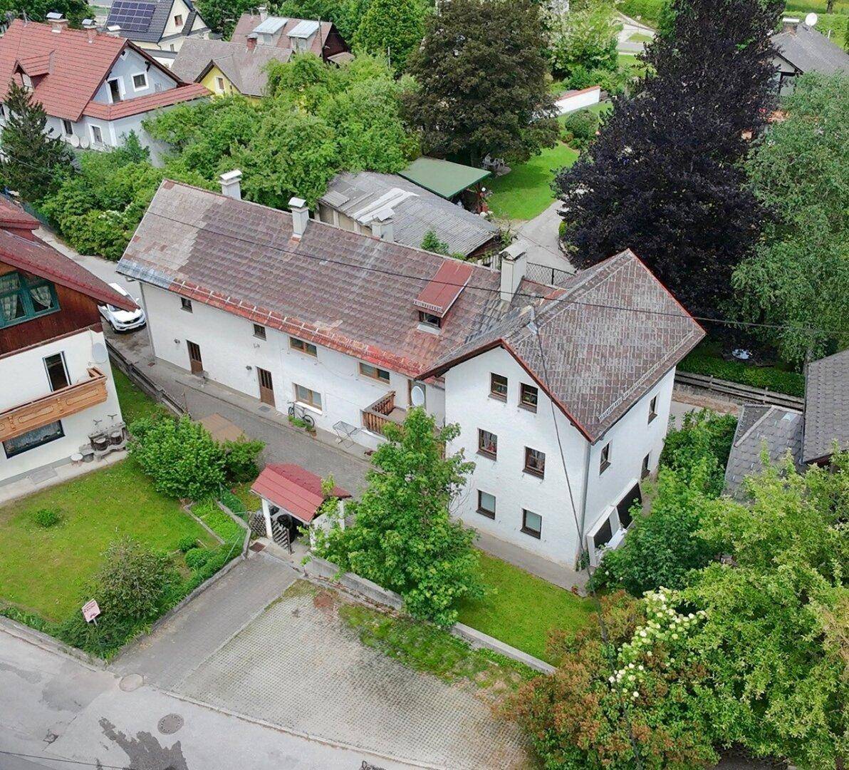 Luftaufnahme des Anwesens mit Garten, umgeben von weiteren Häusern und viel Natur.