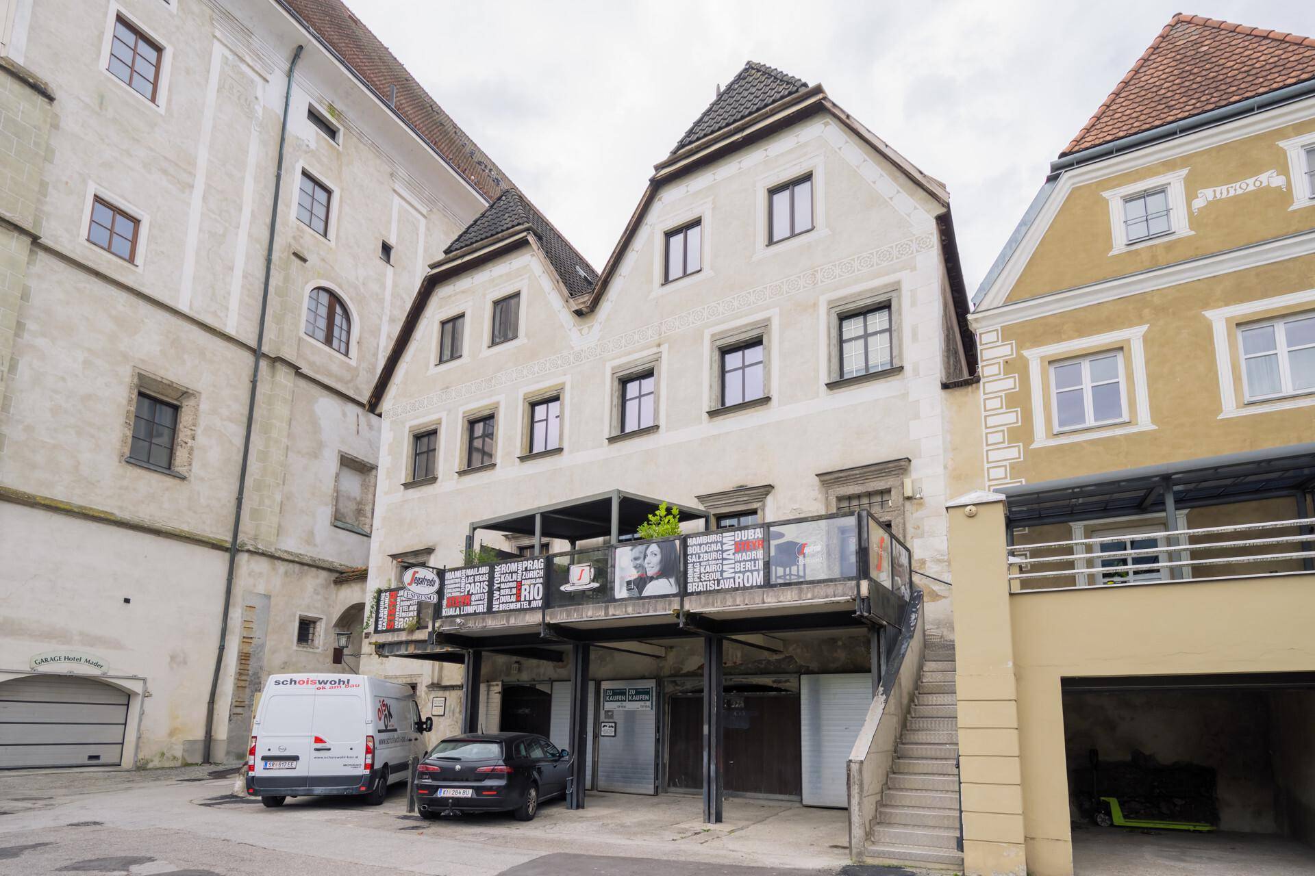 Rückseite eines historischen Gebäudes mit einer modernen Terrassenkonstruktion und Blick auf die Umgebung.