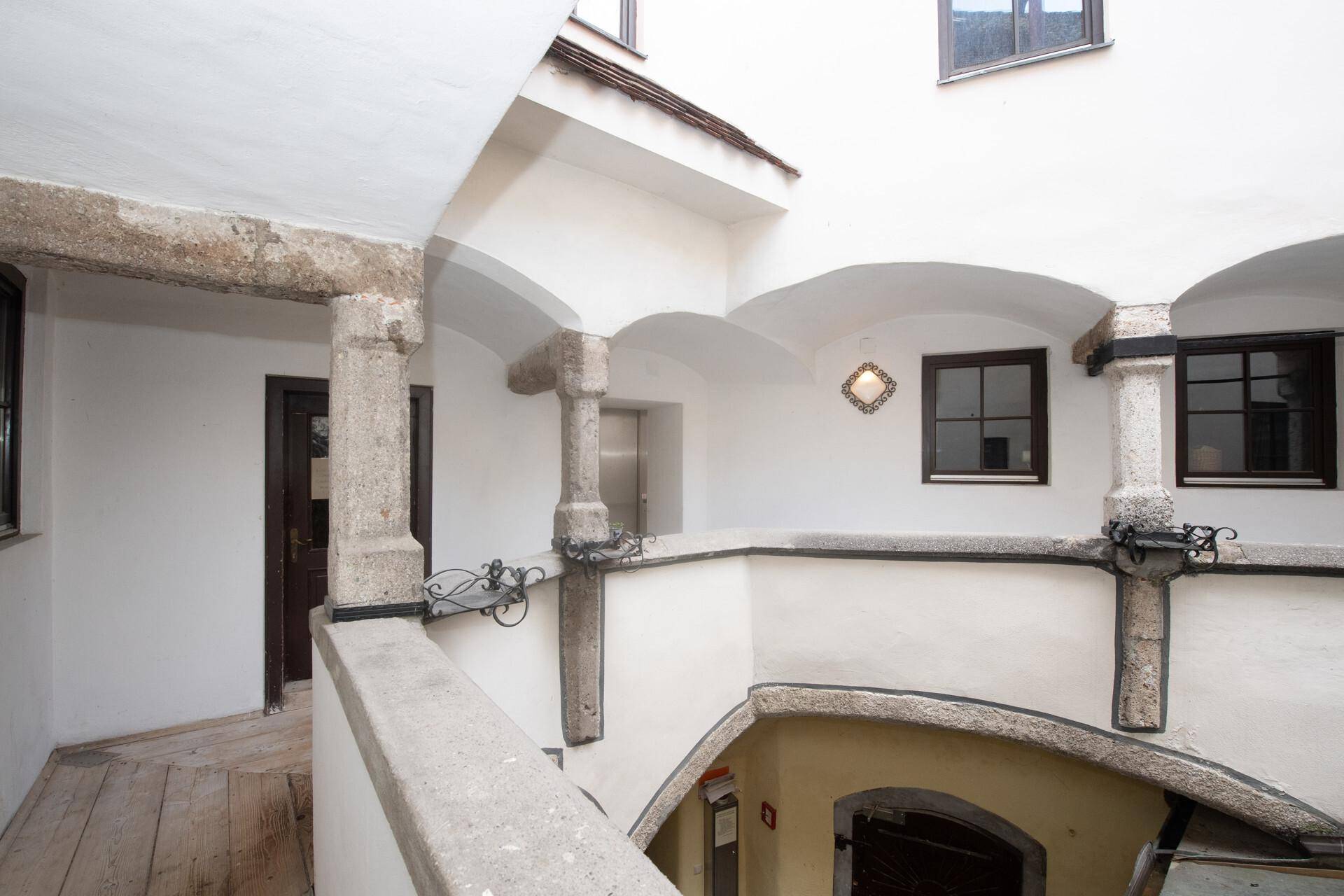 Historischer Innenhof mit Steinsäulen, Gewölbebögen und einem Aufzug im Hintergrund.