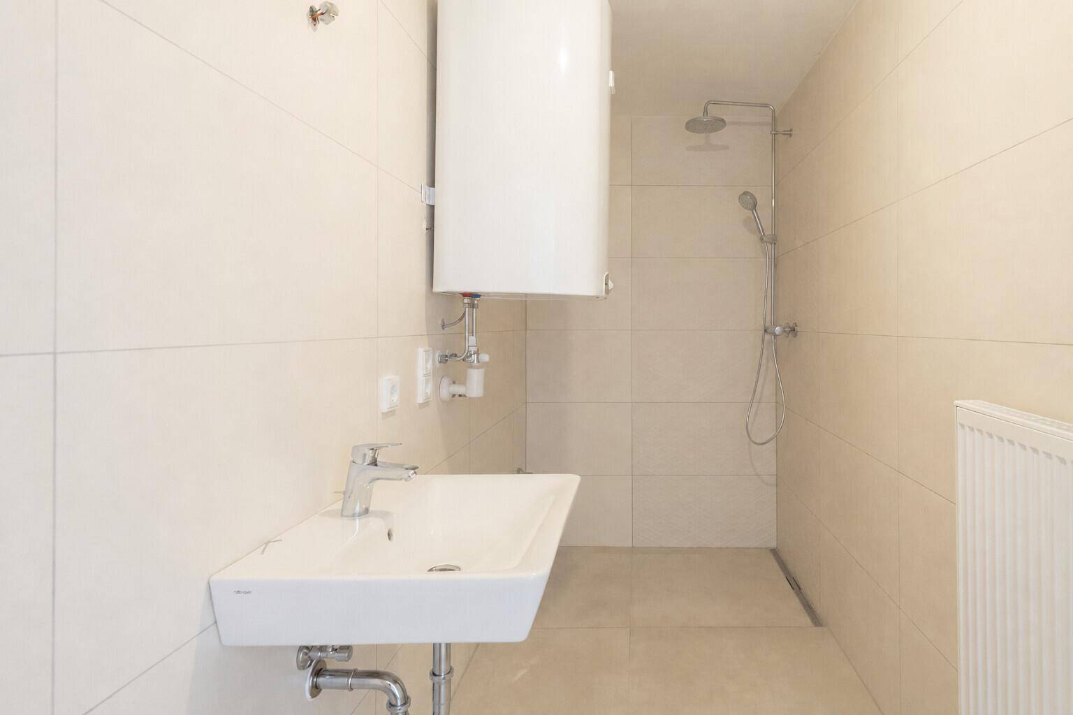 Modernes Badezimmer mit ebenerdiger Dusche, Waschbecken und Boiler an der Wand.
