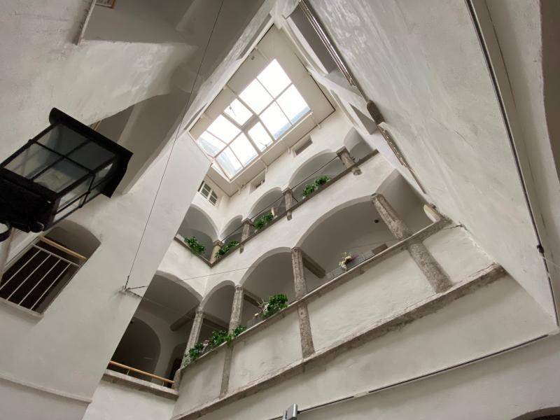 Innenhof mit mehreren Etagen, Arkaden und einem großen Oberlicht, das natürliches Licht spendet.