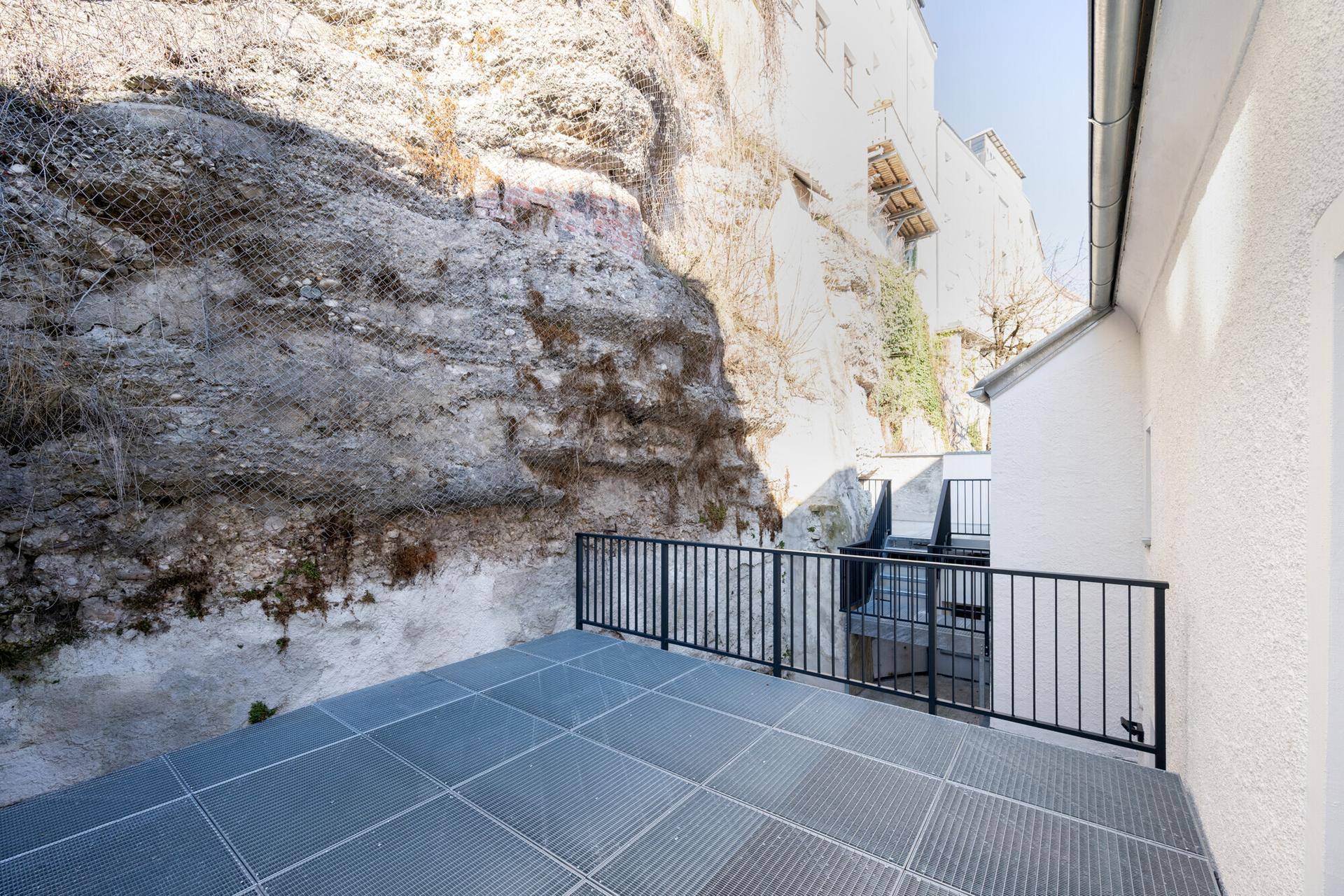 Terrasse mit Metallgitterboden direkt an einer Felswand, bietet einzigartiges Ambiente.