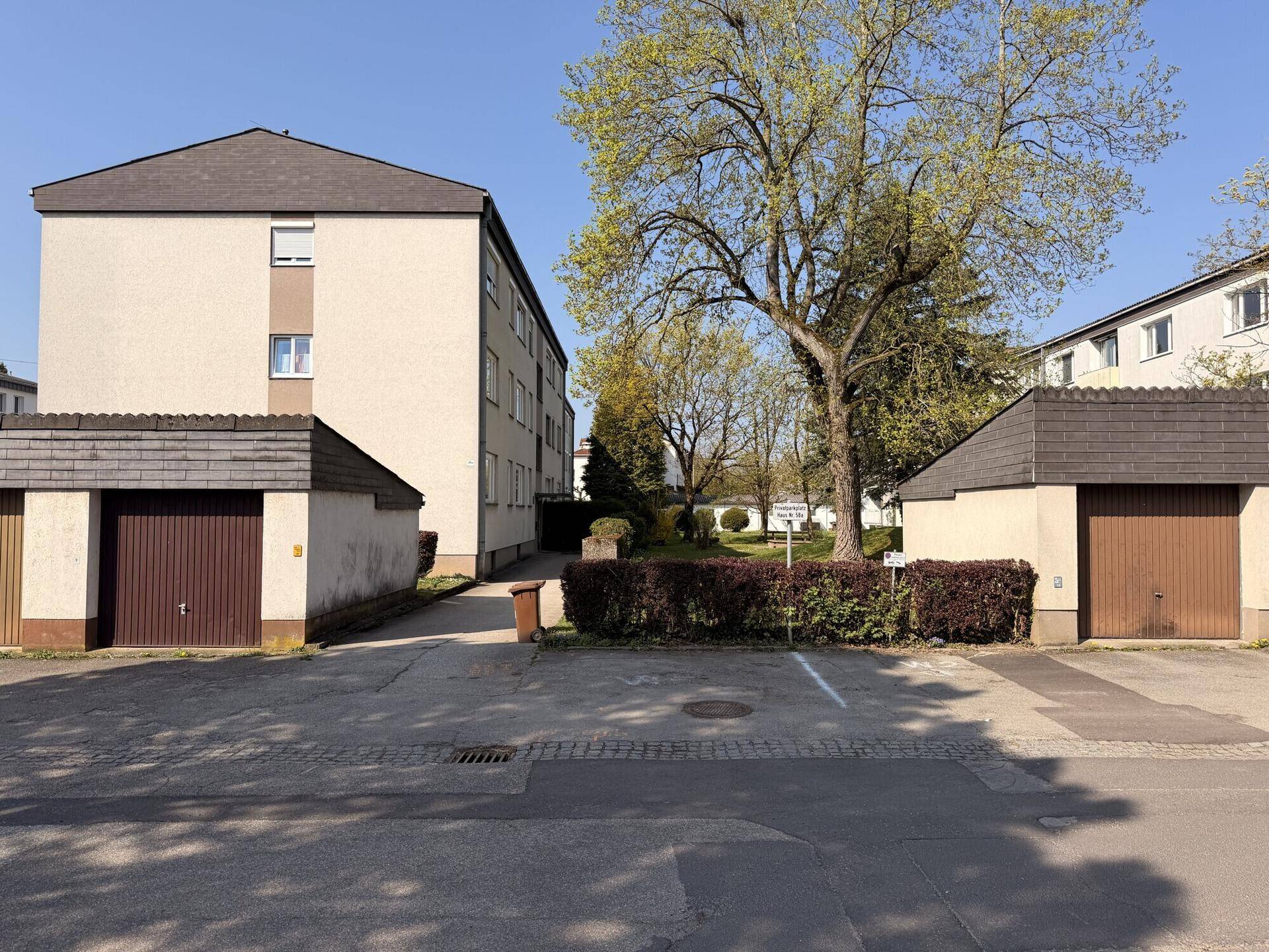 Außenansicht von Garagen und Wohngebäuden mit gepflegter Zufahrt und Grünflächen.