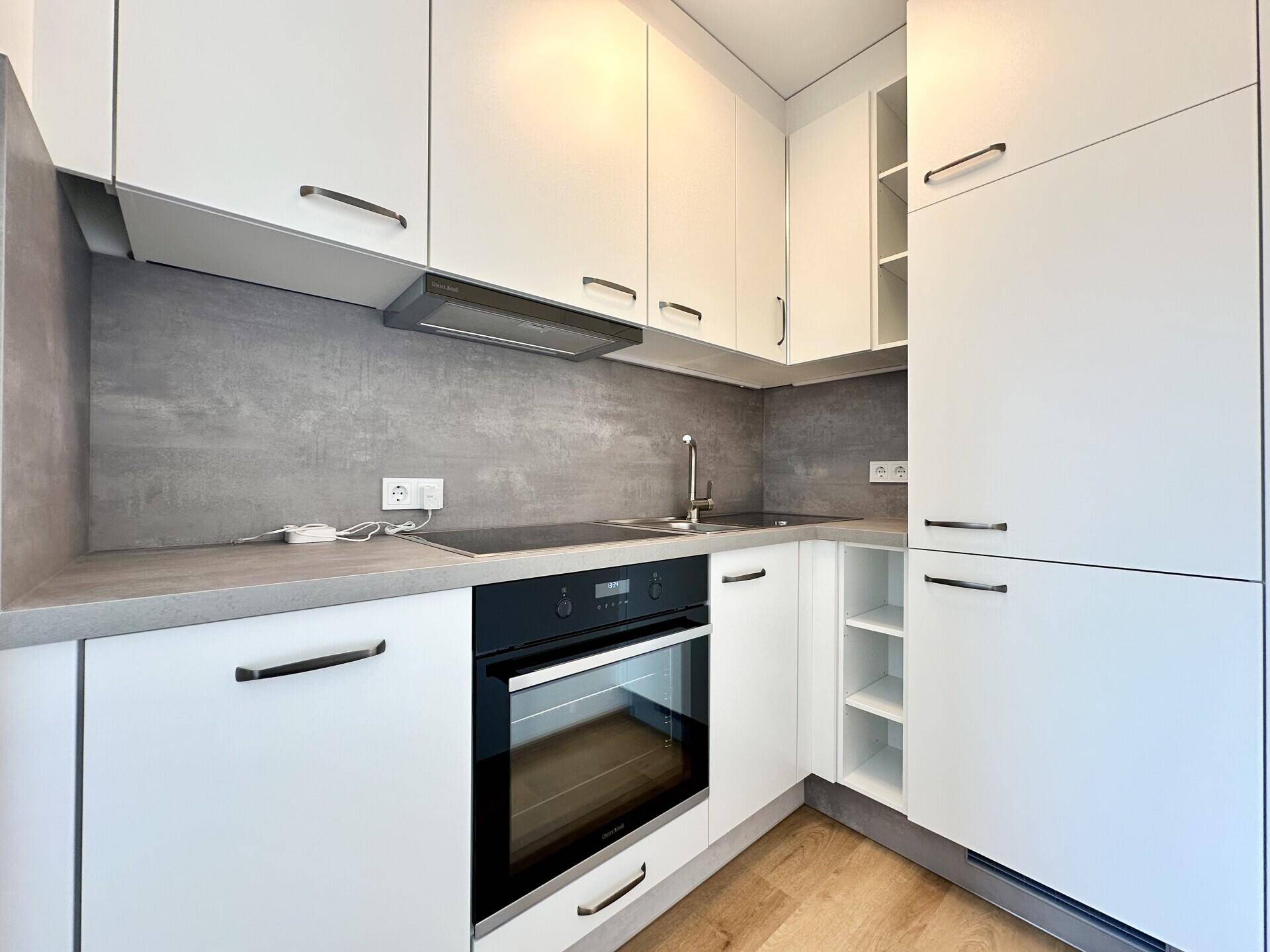 Kompakte, moderne Küche mit weißen Fronten, integriertem Backofen und Kochfeld.