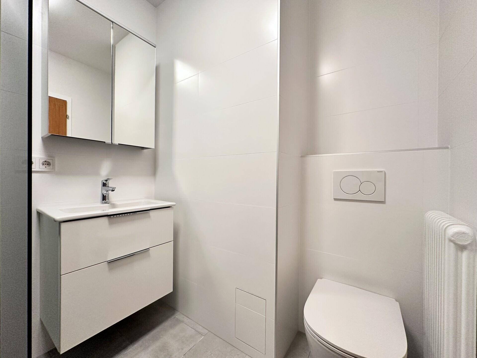 Helles Badezimmer mit wandhängendem WC, Waschtisch und Spiegelschrank.