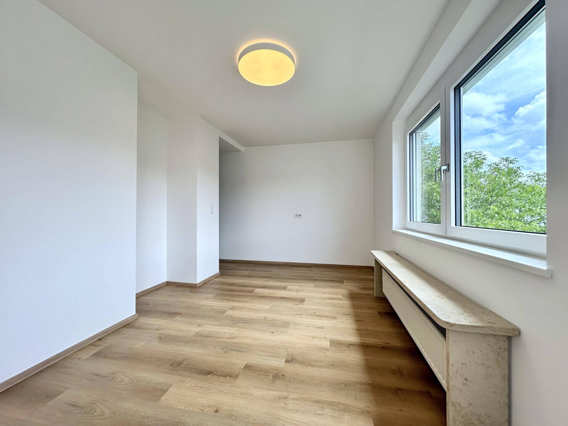 Geräumiges, helles Zimmer mit Laminatboden und großem Fenster, das eine weite Aussicht bietet.