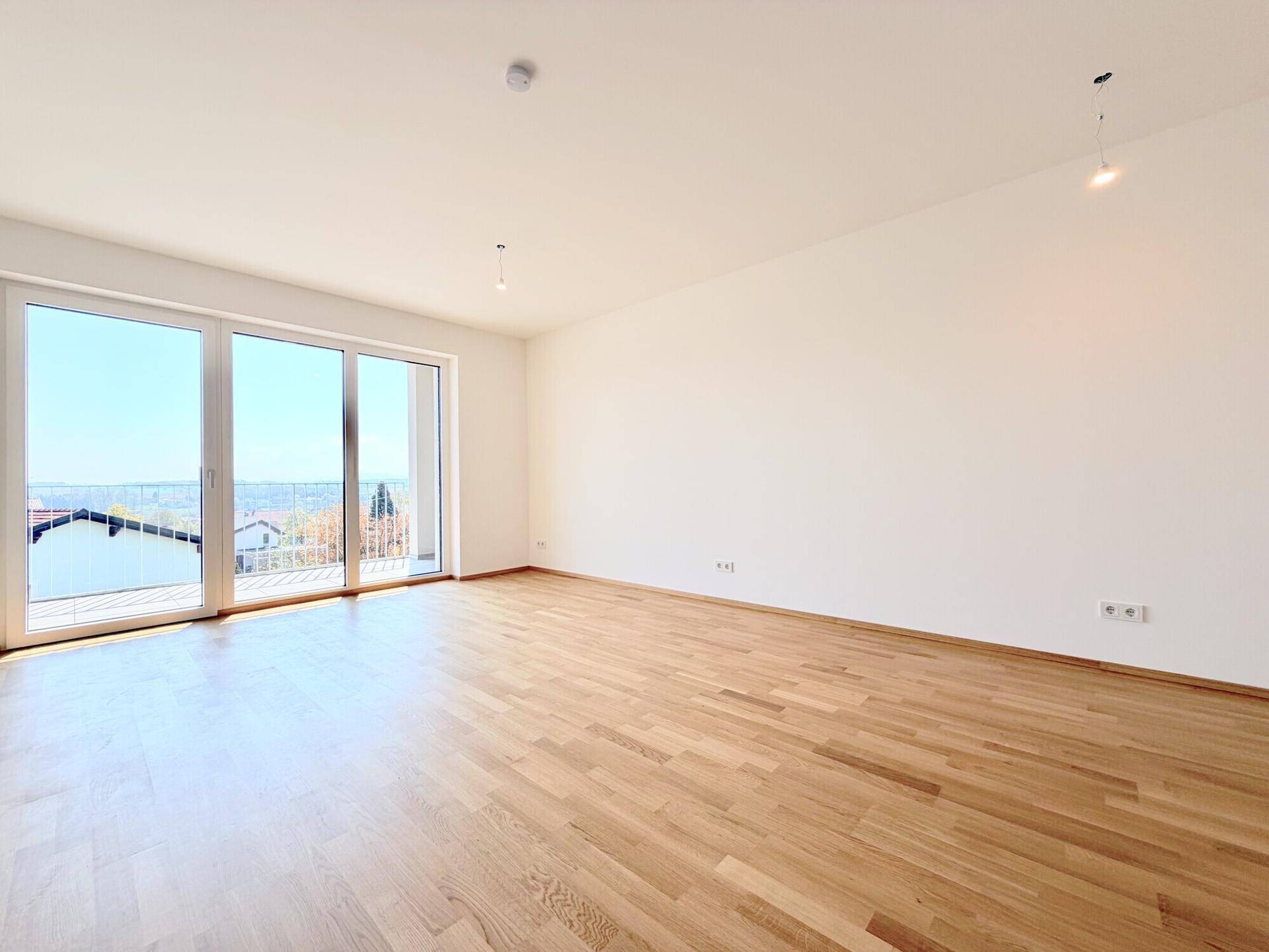 Geräumiger, heller Raum mit Holzboden und großen Fenstern, die einen weiten Blick ermöglichen.