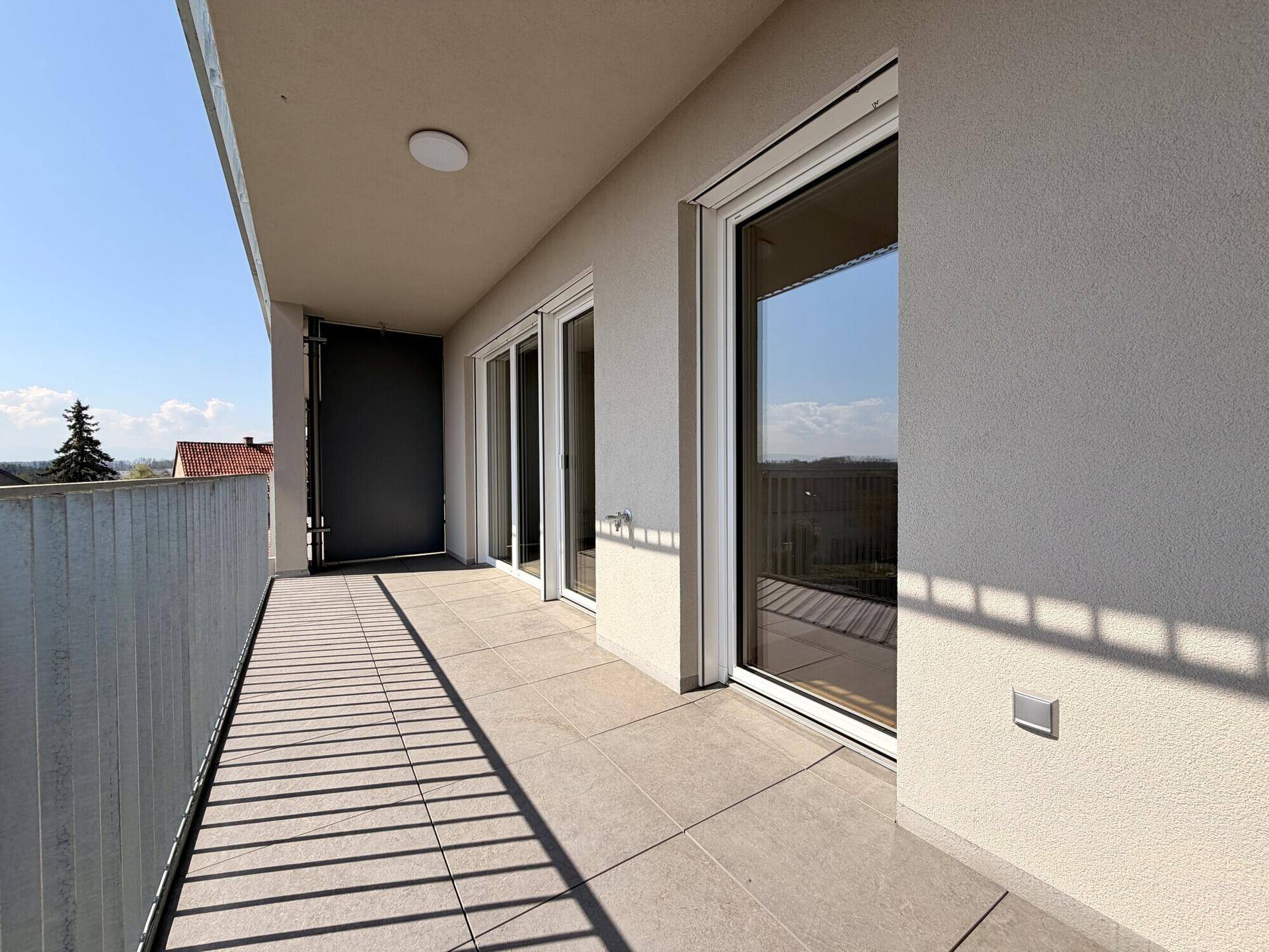 Heller Balkon mit Fliesenboden und modernem Geländer, ideal für entspannte Stunden im Freien.