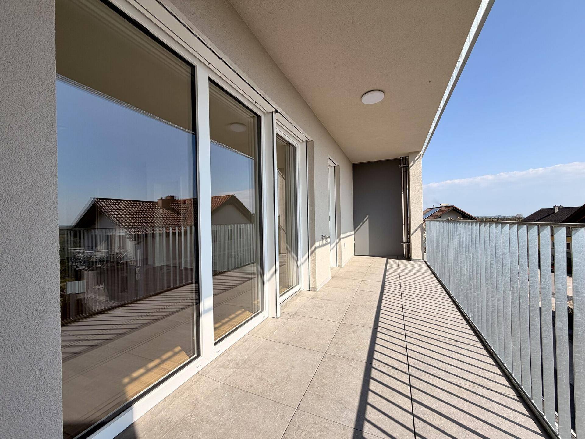 Moderner Balkon mit Fliesenboden und Metallgeländer, bietet einen schönen Ausblick.