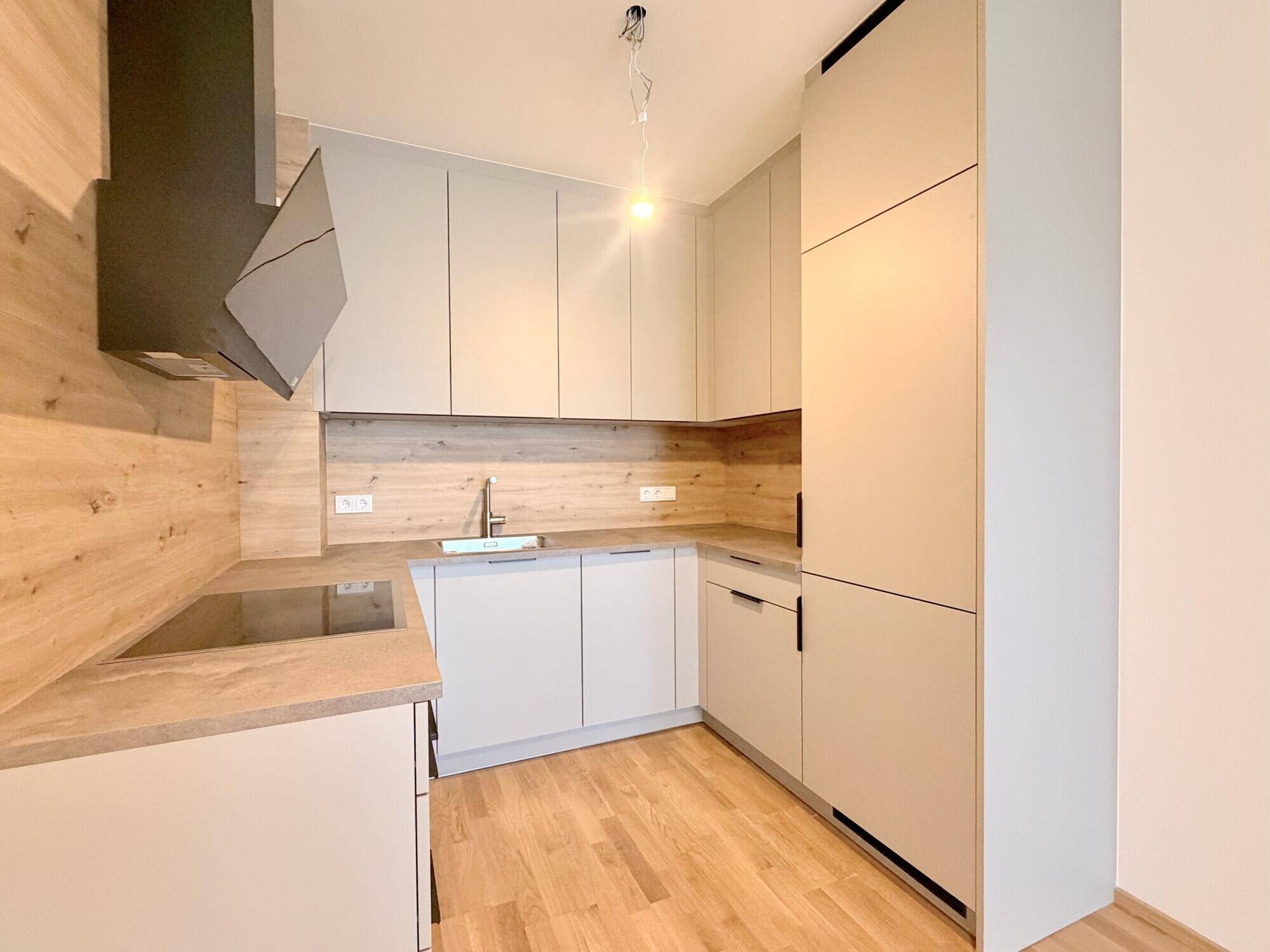 Helle, moderne Küche mit integrierten Geräten, Holzdetails und Induktionskochfeld in neuwertigem Zustand.