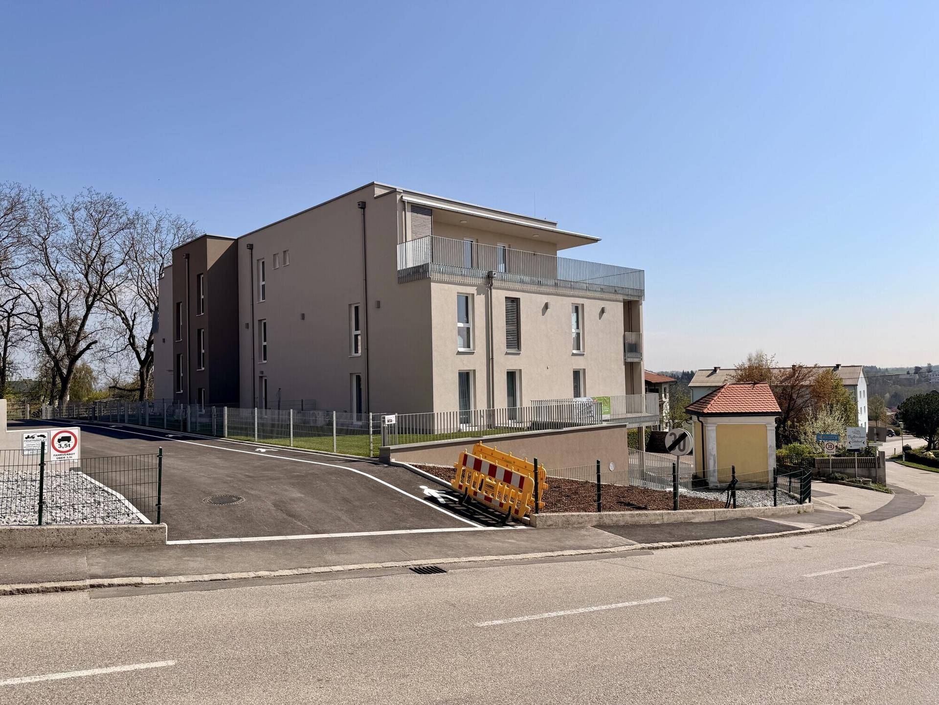 Seitenansicht eines modernen Mehrfamilienhauses mit Balkonen und gepflegter Außenanlage.