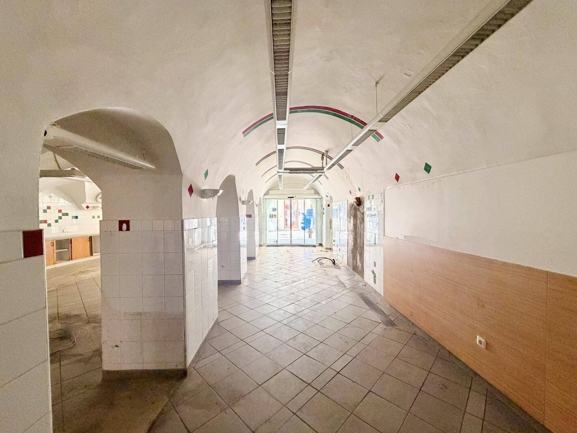 Langer, heller Raum mit Gewölbedecken und gefliestem Boden, geeignet für verschiedene gewerbliche Nutzungen.