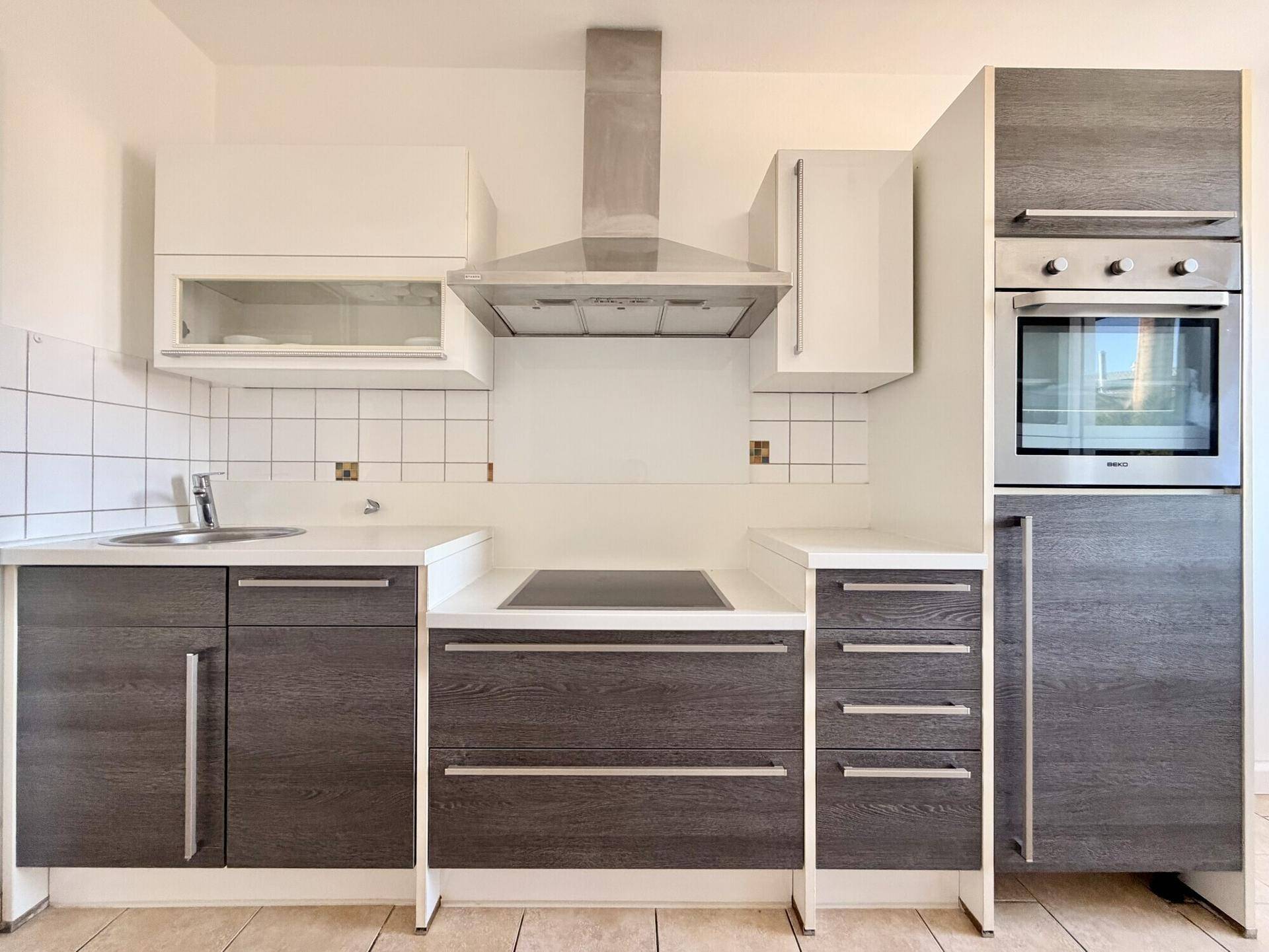 Moderne Einbauküche mit dunklen Holzfronten, integriertem Backofen und Induktionskochfeld.
