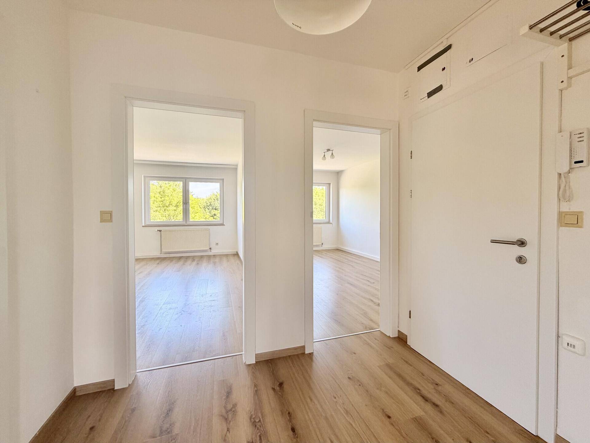 Heller Flur mit Laminatboden und offenen Durchgängen zu den angrenzenden Wohnbereichen.