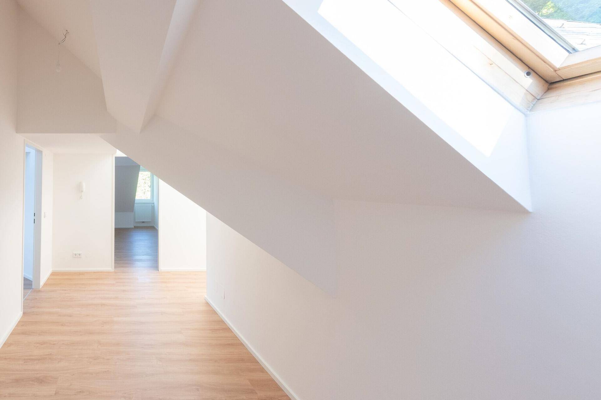Heller Flur im Dachgeschoss mit Laminatboden, schrägen Wänden und Dachfenster.