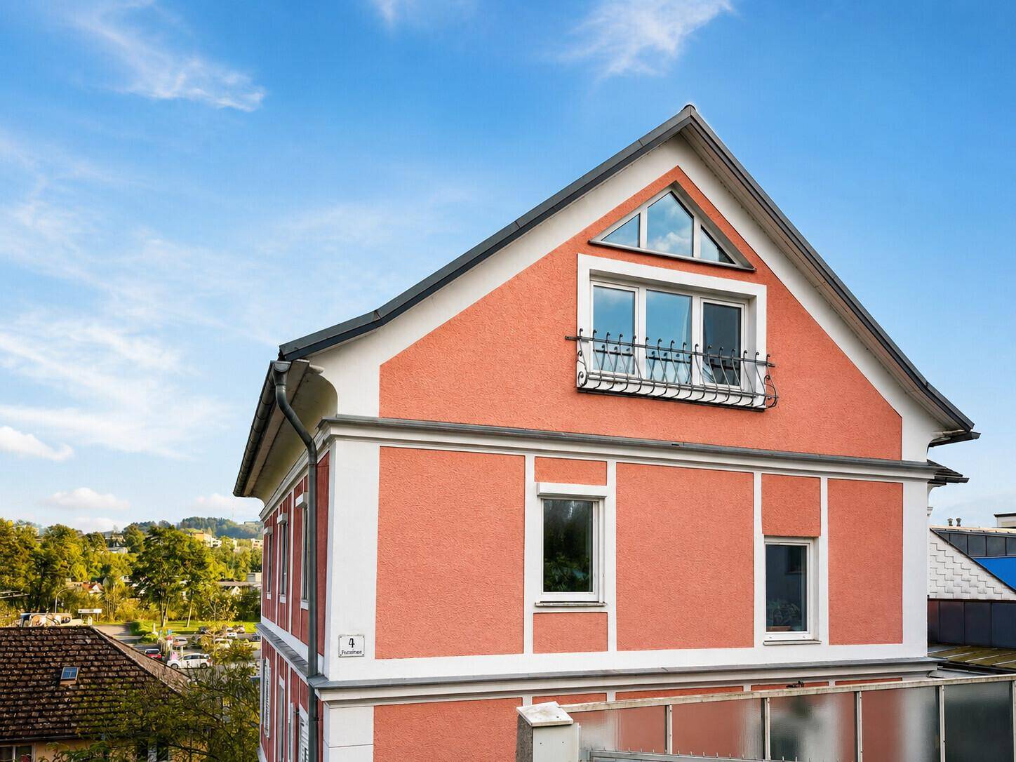 Außenansicht des Gebäudes mit terrakottafarbener Fassade unter blauem Himmel.