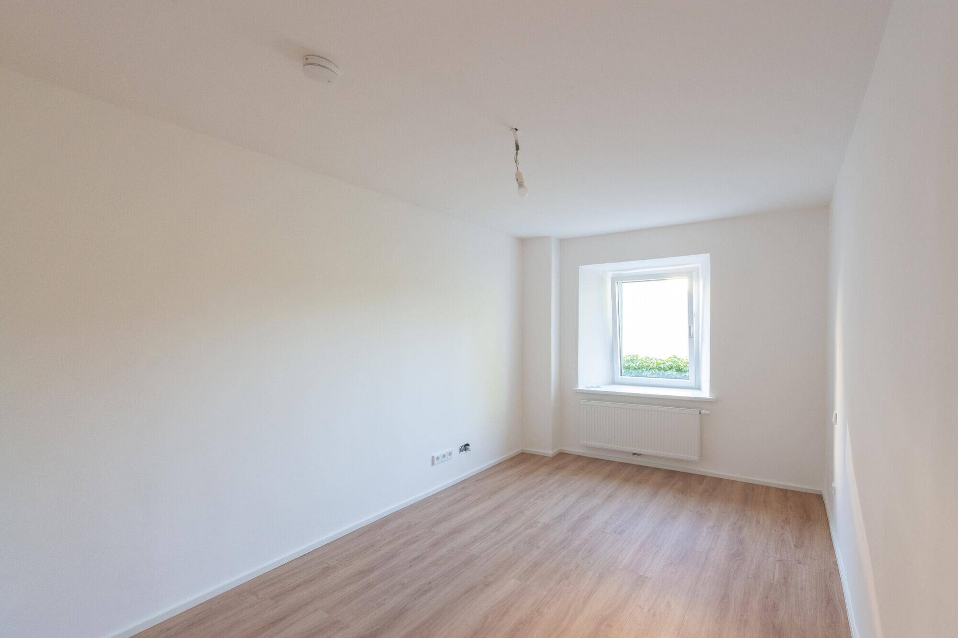 Gemütliches Zimmer mit Laminatboden und einem Fenster, perfekt als Kinder- oder Gästezimmer.