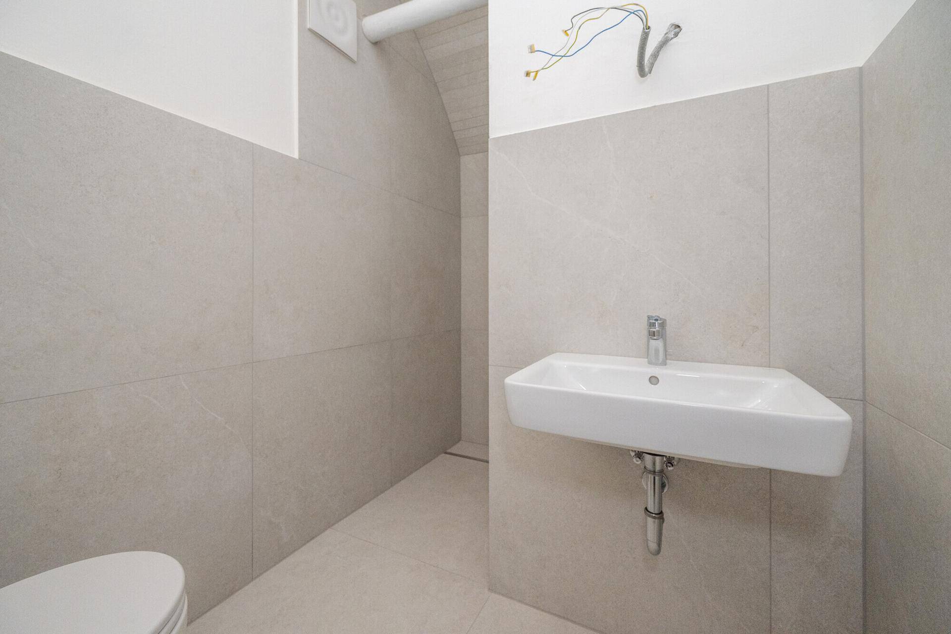 Helles WC mit modernem Waschbecken und Fliesen, sauber und funktional gestaltet.
