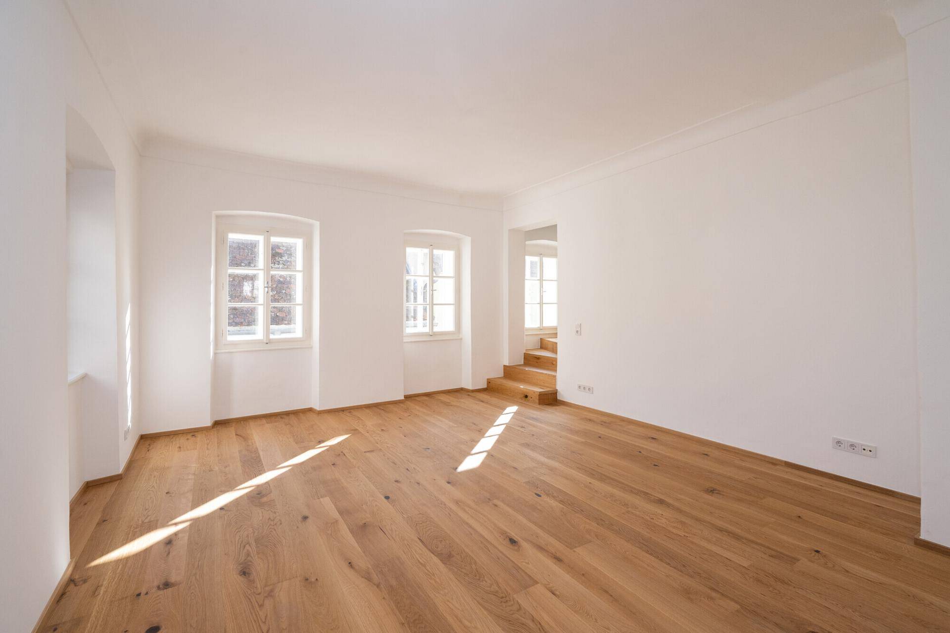 Geräumiger, heller Raum mit Holzboden und viel Tageslicht, bereit zur Einrichtung.