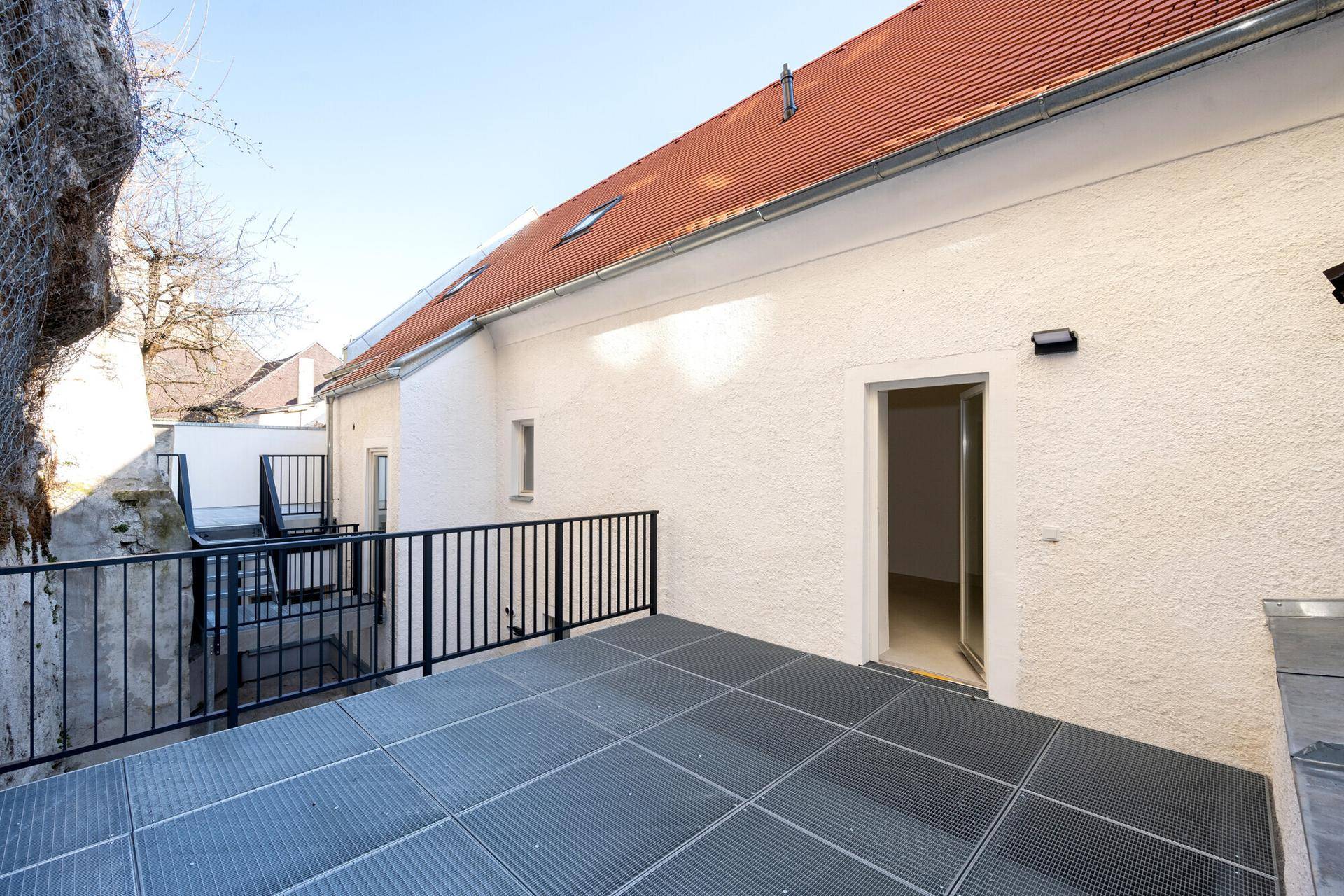 Große Außenterrasse mit Metallgitterboden und Zugang zum Gebäude.