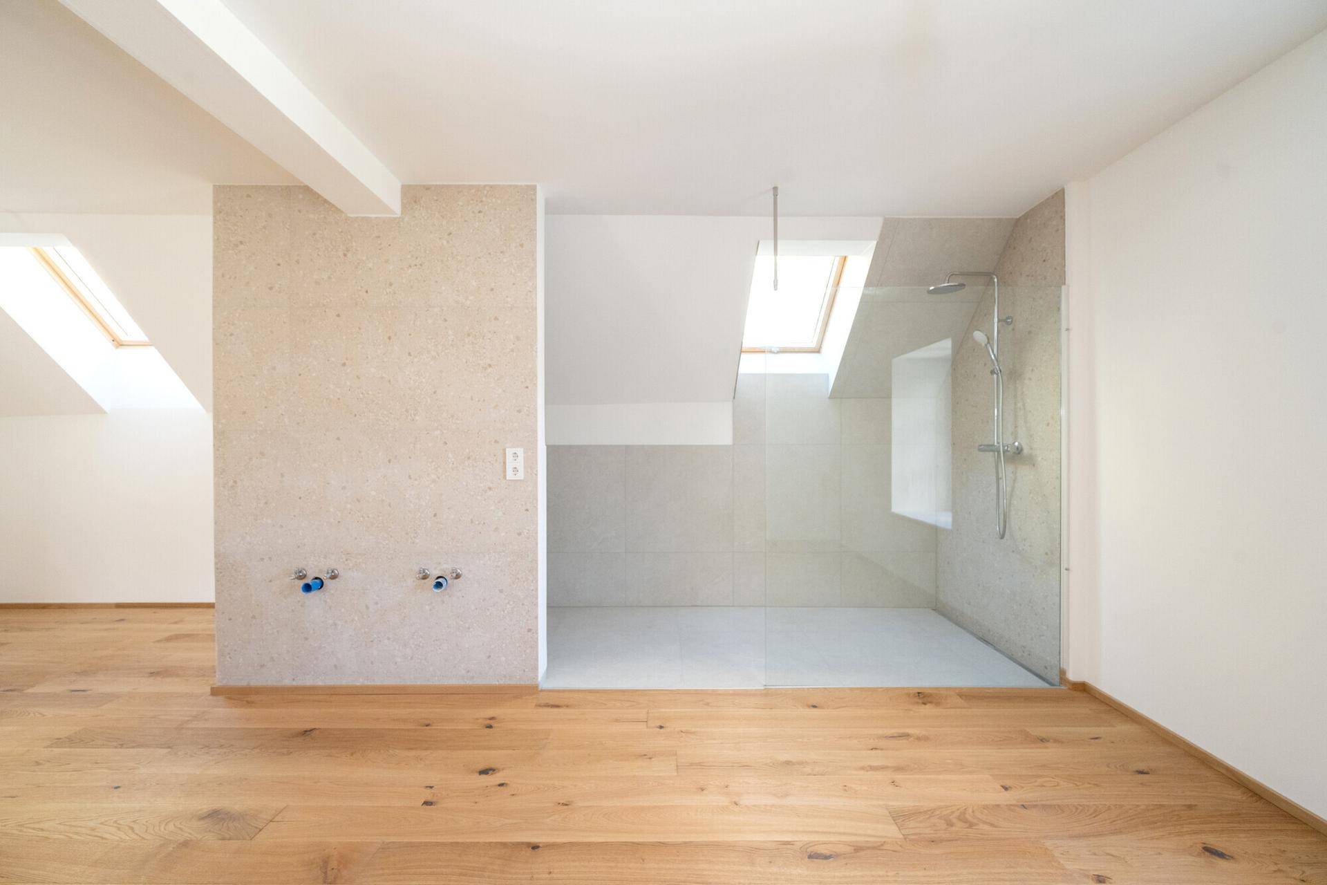 Helles Badezimmer im Dachgeschoss mit begehbarer Dusche und Dachfenstern.