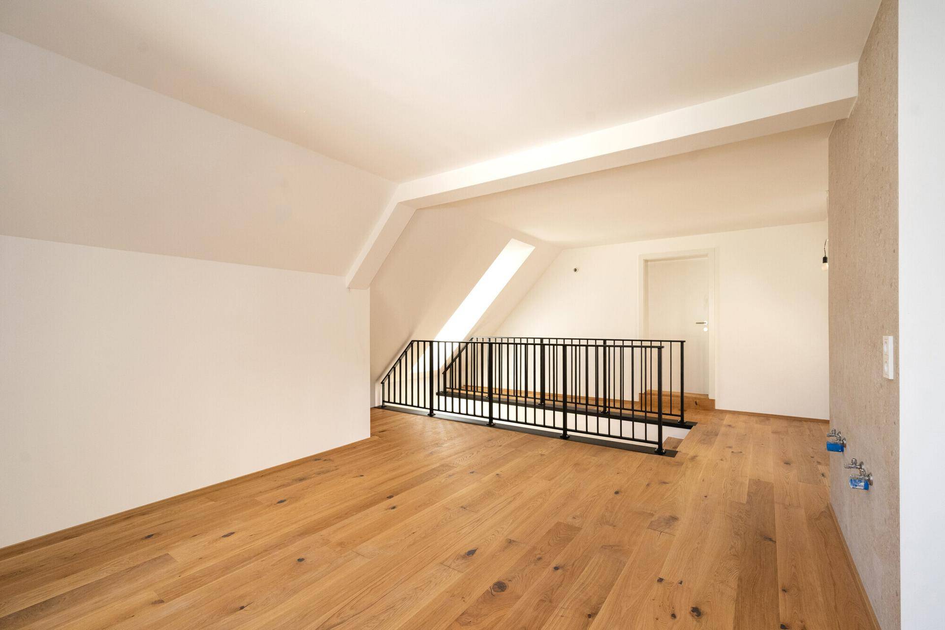 Geräumiges Dachgeschoss mit Holzboden und Dachfenster, ideal für offene Wohnkonzepte.