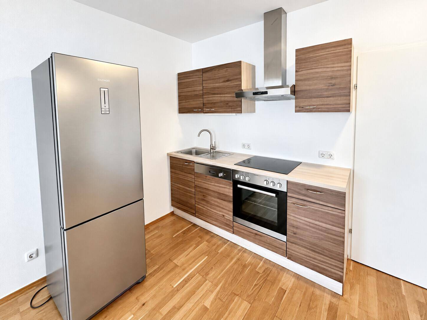 Kompakte Küche mit Holzschränken, Edelstahlgeräten und einem großen Kühlschrank, funktional und stilvoll.