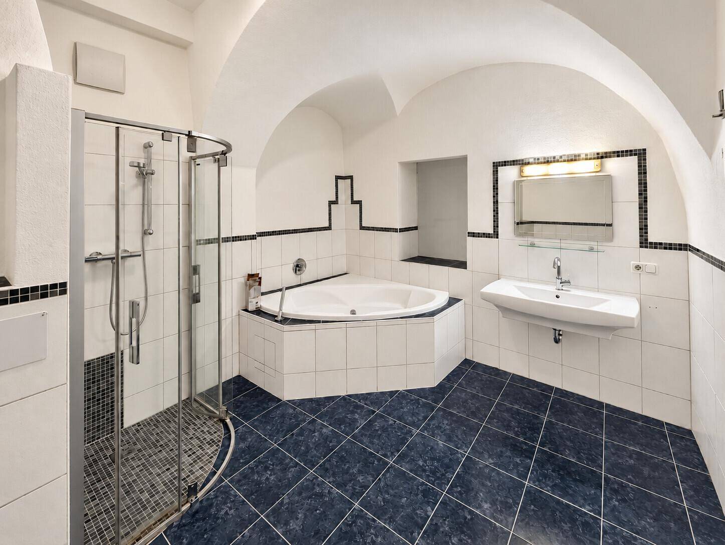 Helles Badezimmer mit Badewanne, Duschkabine und Waschbecken, ausgestattet mit blauen Fliesen und Spiegel.